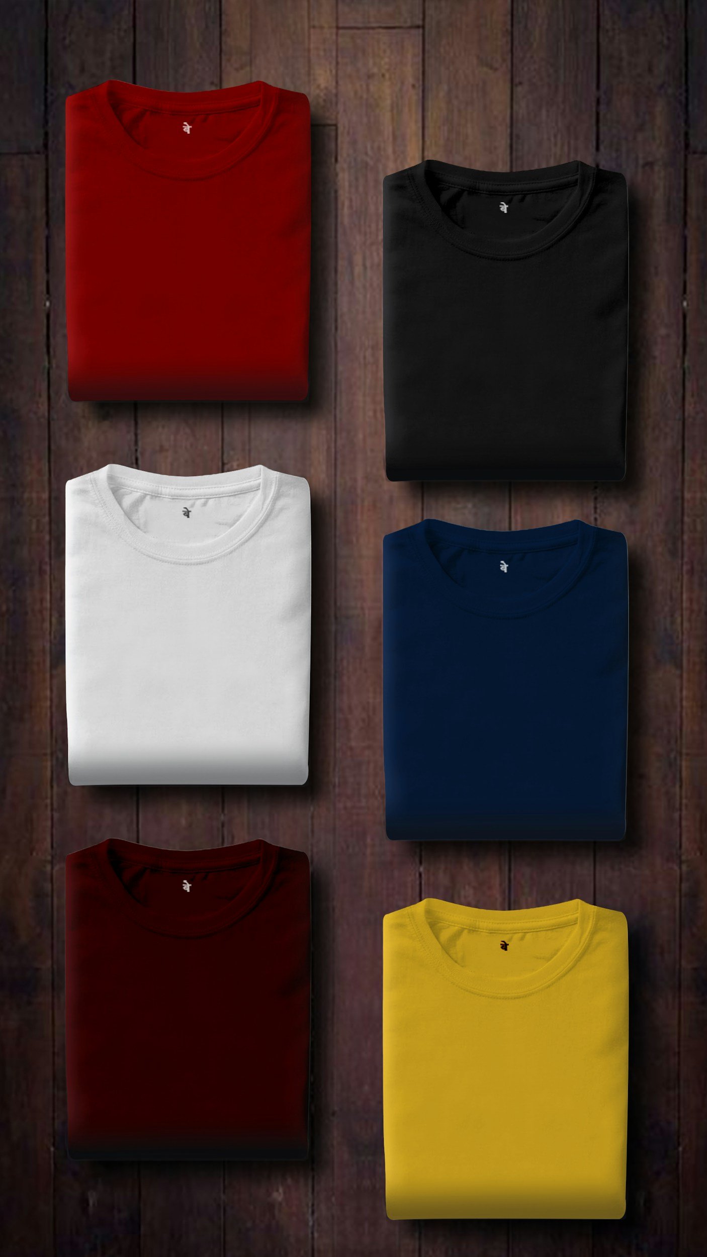Five folded t-shirts in red, black, white, navy blue, and yellow colors arranged on a wooden surface. tshirt printing services