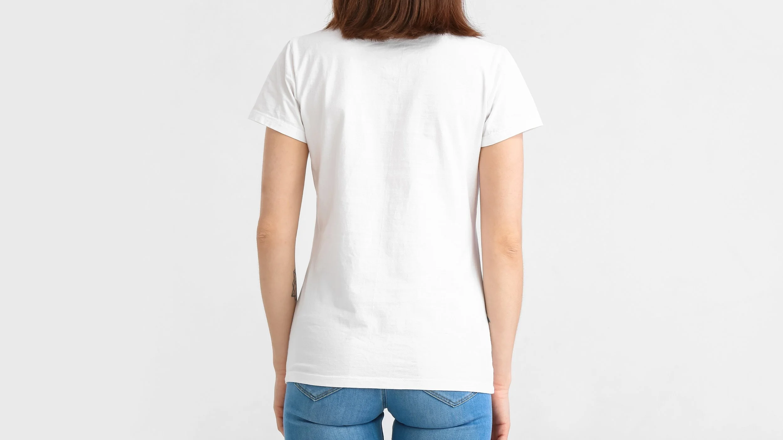 Person wearing a white T-shirt and blue jeans, viewed from the back.workware printing and embroidery services link it