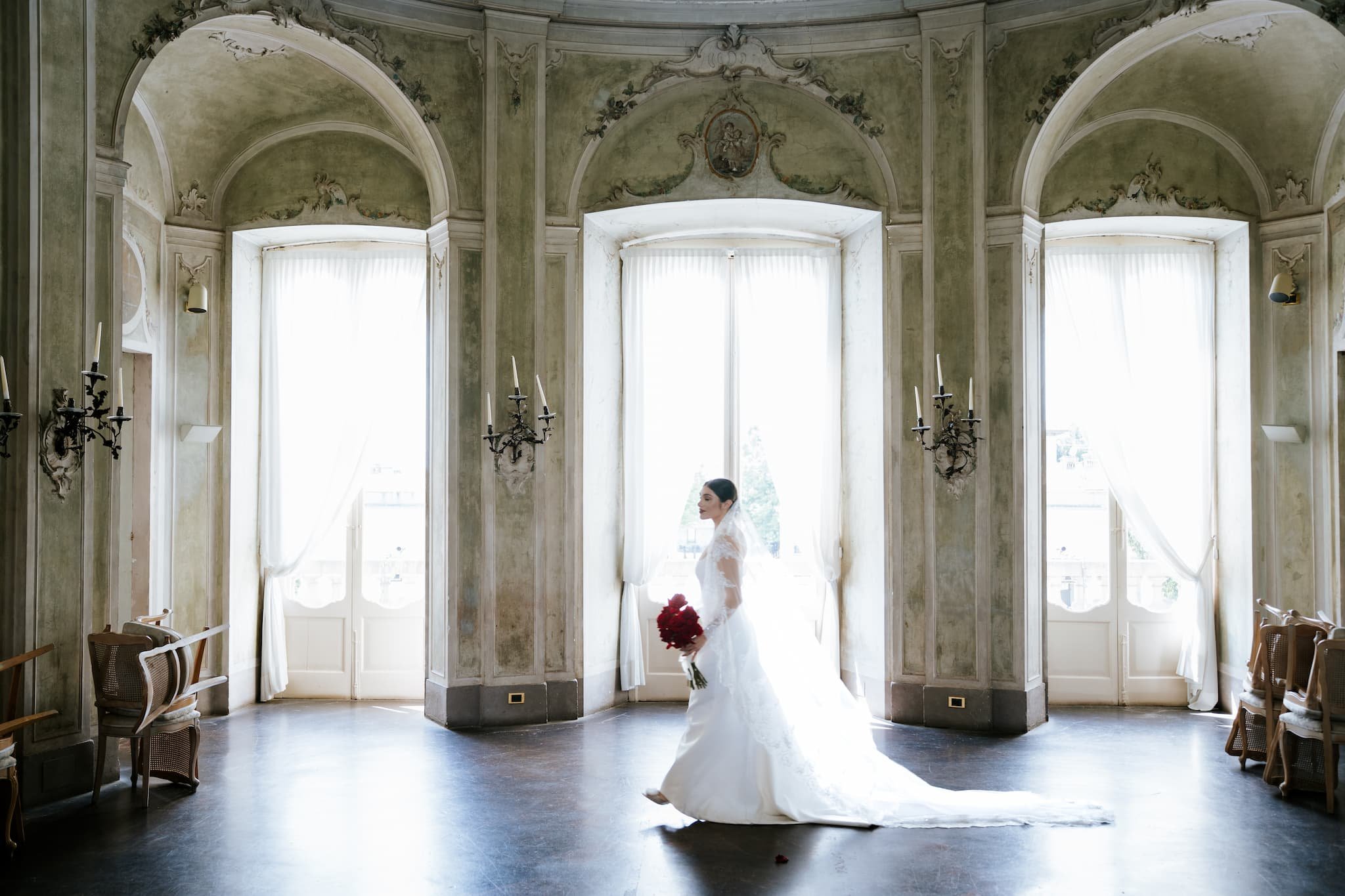 Bride standing in an ornate historic Lake Como villa room with tall windows, natural light, and elegant architecture.
