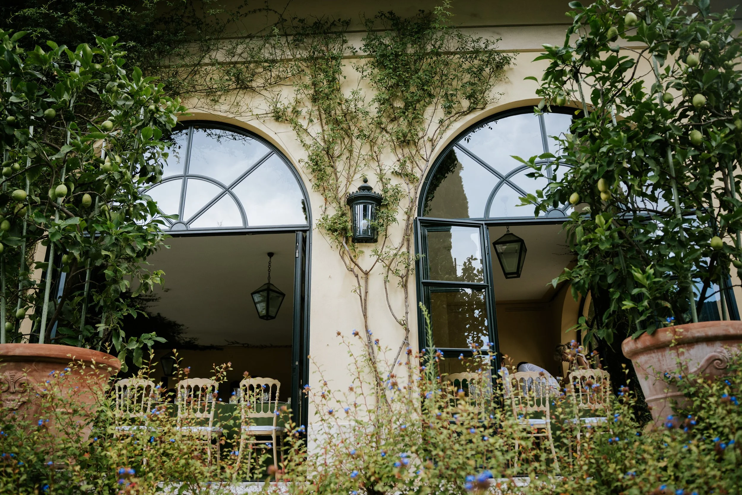 Arched windows and French doors at Villa del Balbianello's loggia, set up for a wedding ceremony with rows of chairs.