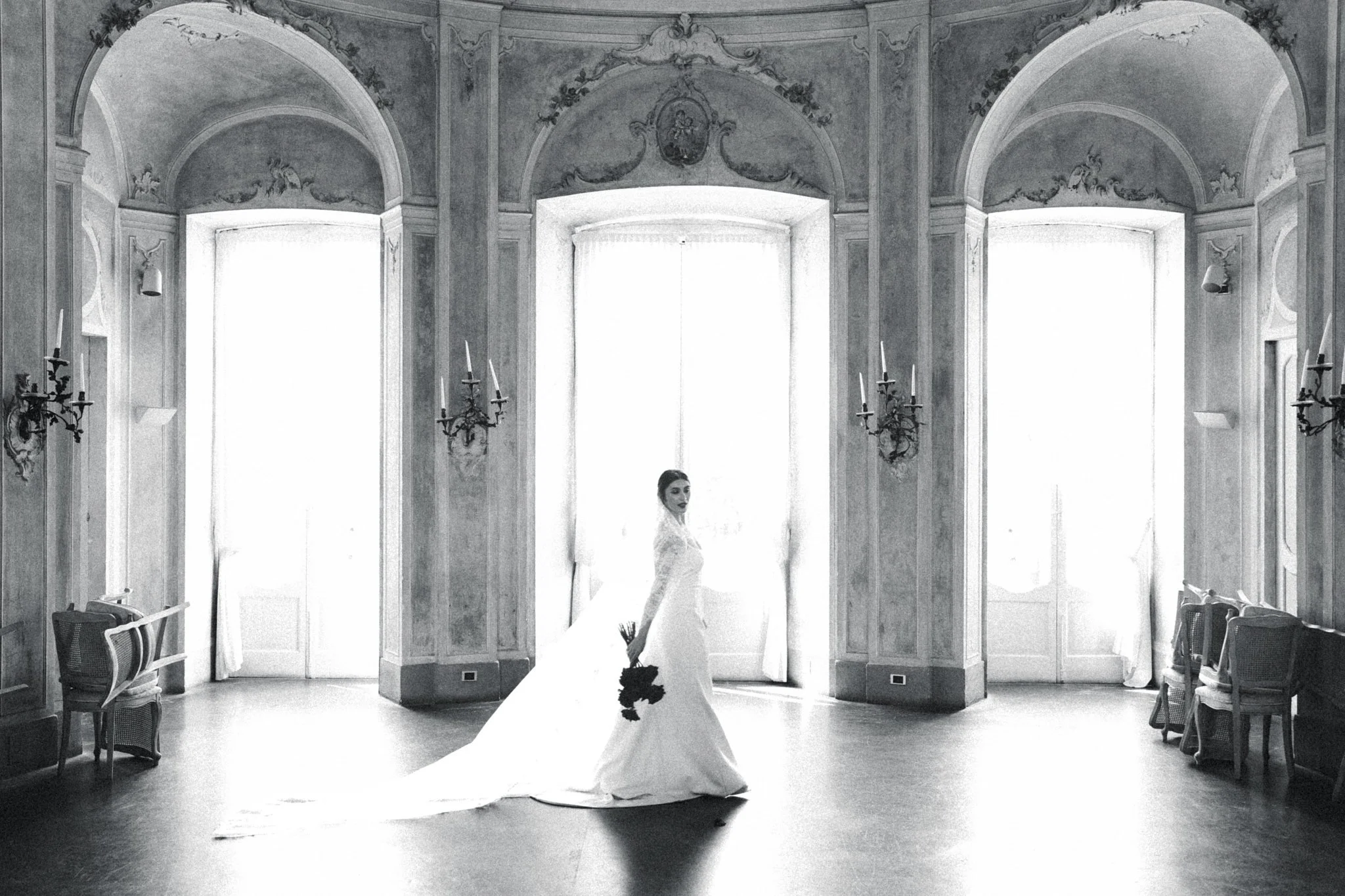 Bride standing in an ornate historic Lake Como villa room with tall windows, natural light, and elegant architecture.