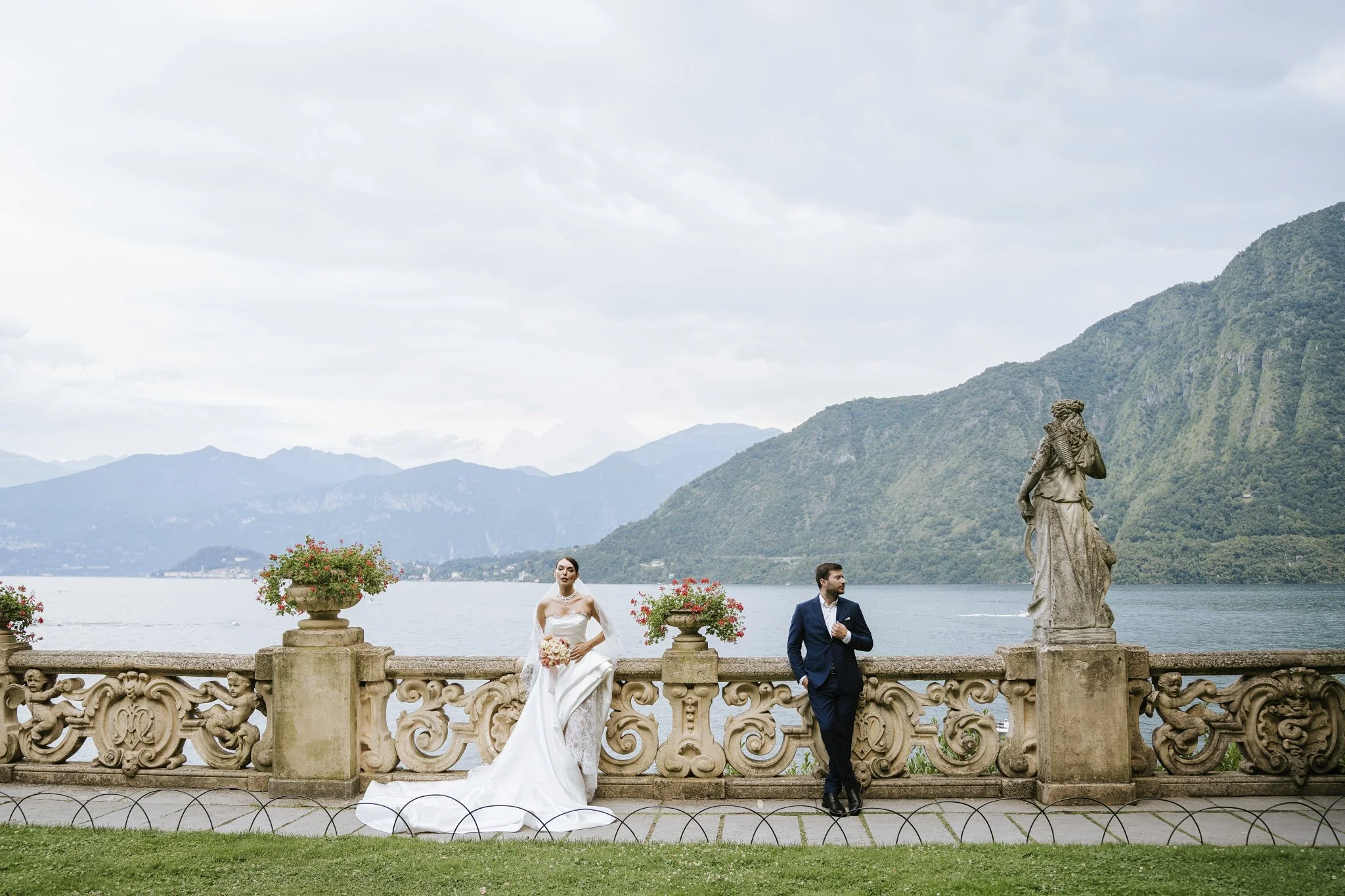 Bride and groom on the loggia terrace at Villa del Balbianello, Lake Como, with the balustrade and lake views behind them.