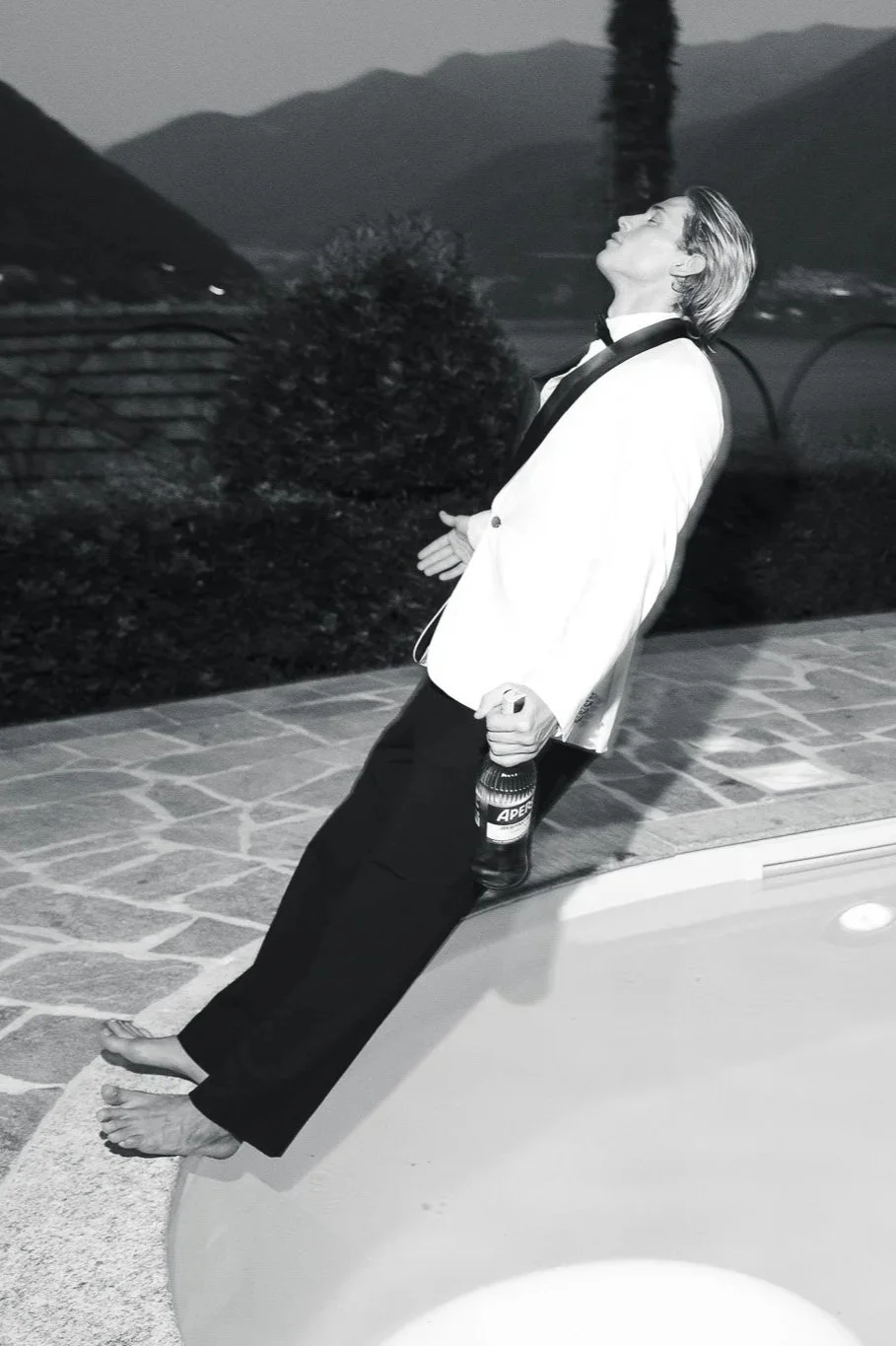 editorial wedding groom jumping in the pool near lake como