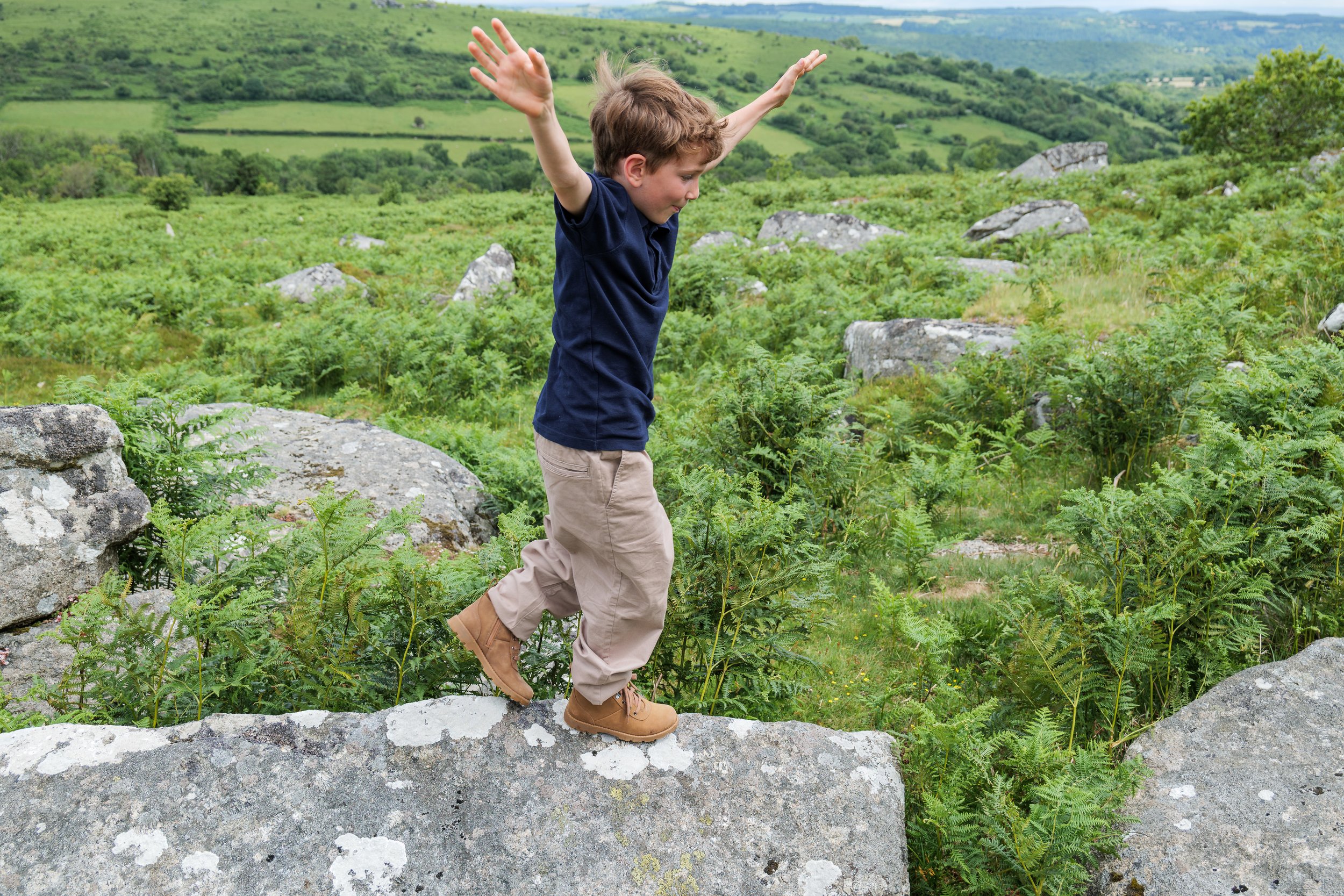 A young boy jumping and playing on Dartmoor.