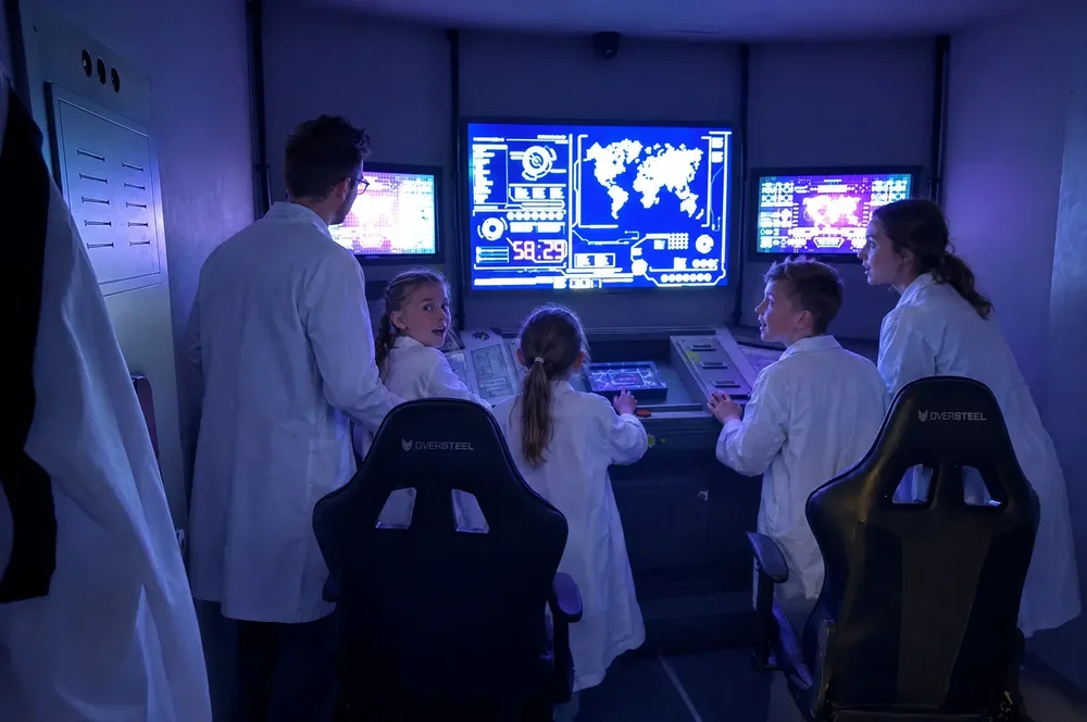 Kids in lab coats at the Mission Control console during an escape room birthday party at Escape London