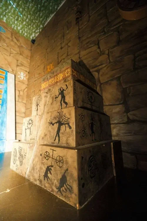 A painted stepped pyramid covered in ancient figures in Mayan Temple — Escape London Whitechapel