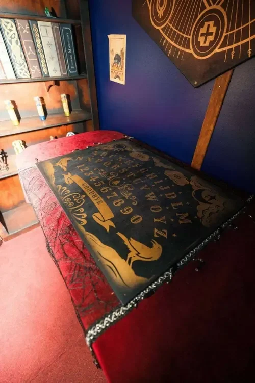 The séance room with an ouija board and spell shelves in Young Wednesday — Escape London Hammersmith