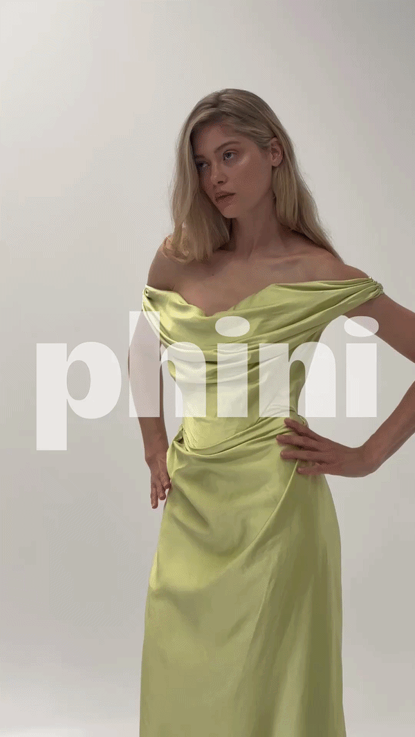 A young woman with long blonde hair wearing a light yellow satin off-shoulder gown, posing against a plain light gray background.