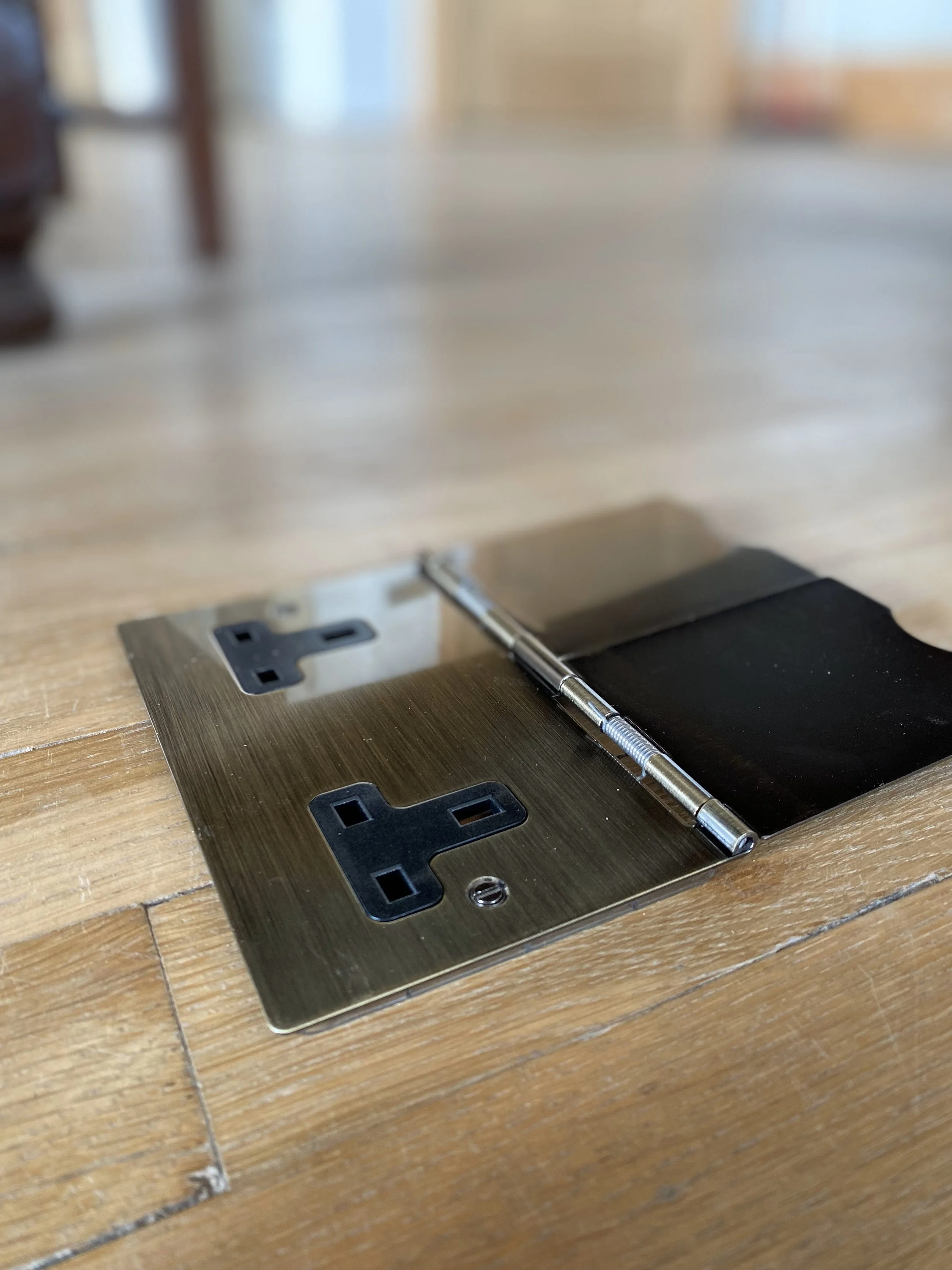 Close-up of a door lock mechanism with a metallic plate and a screwdriver resting on a wooden floor.