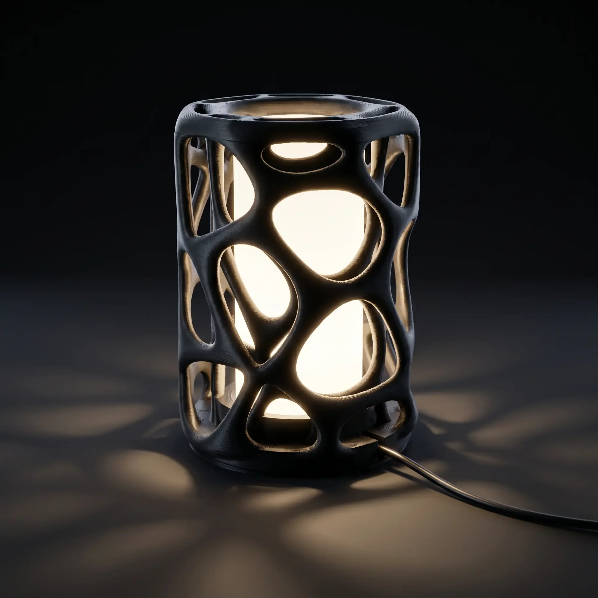 Black 3D-printed cylinder lamp emitting a soft, warm amber glow and casting ambient shadows.