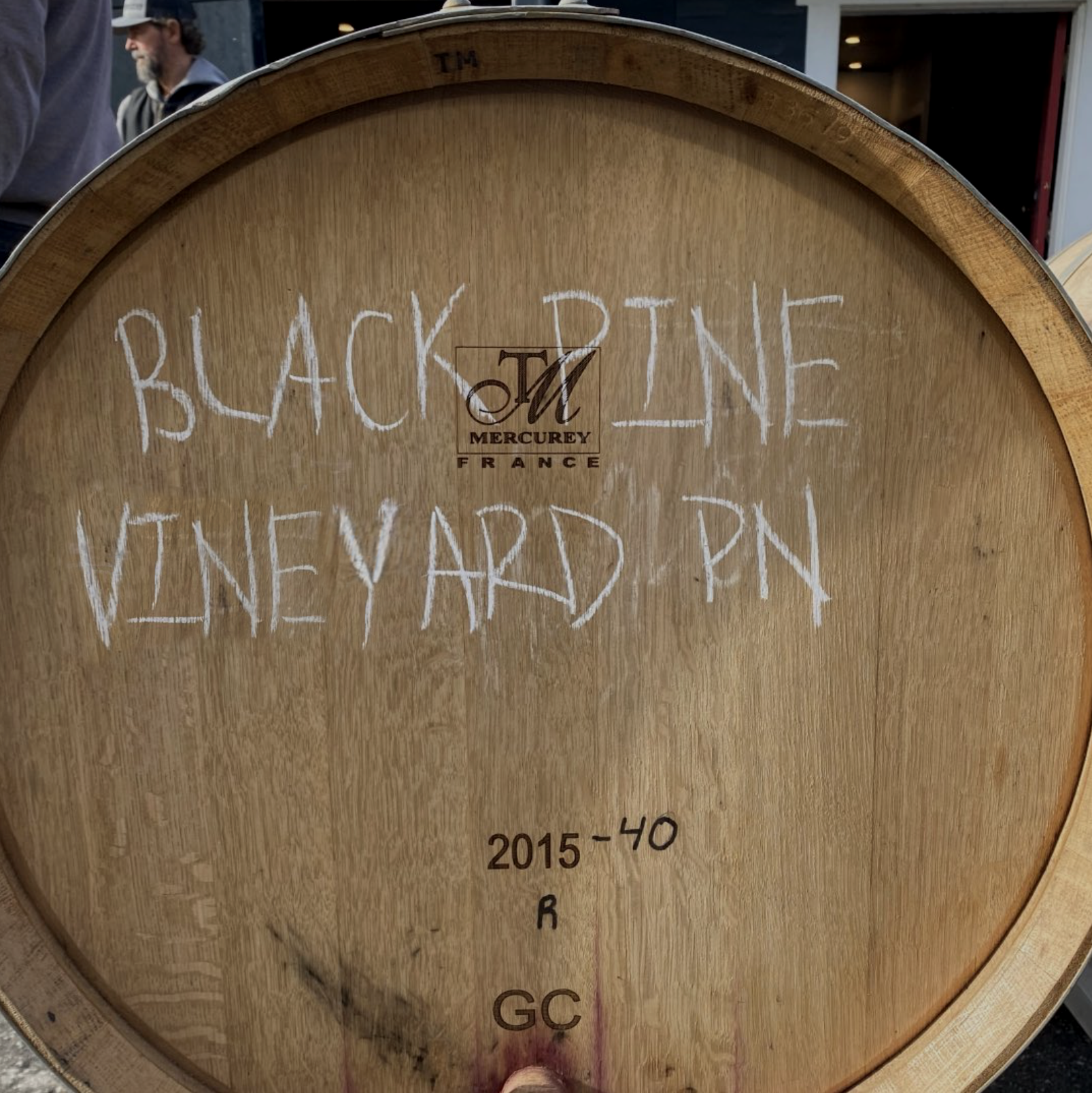Close-up of a wooden wine barrel with handwritten chalk markings indicating wine details, including vintage years from 2015 to 2016 and the region Bordeaux, France.