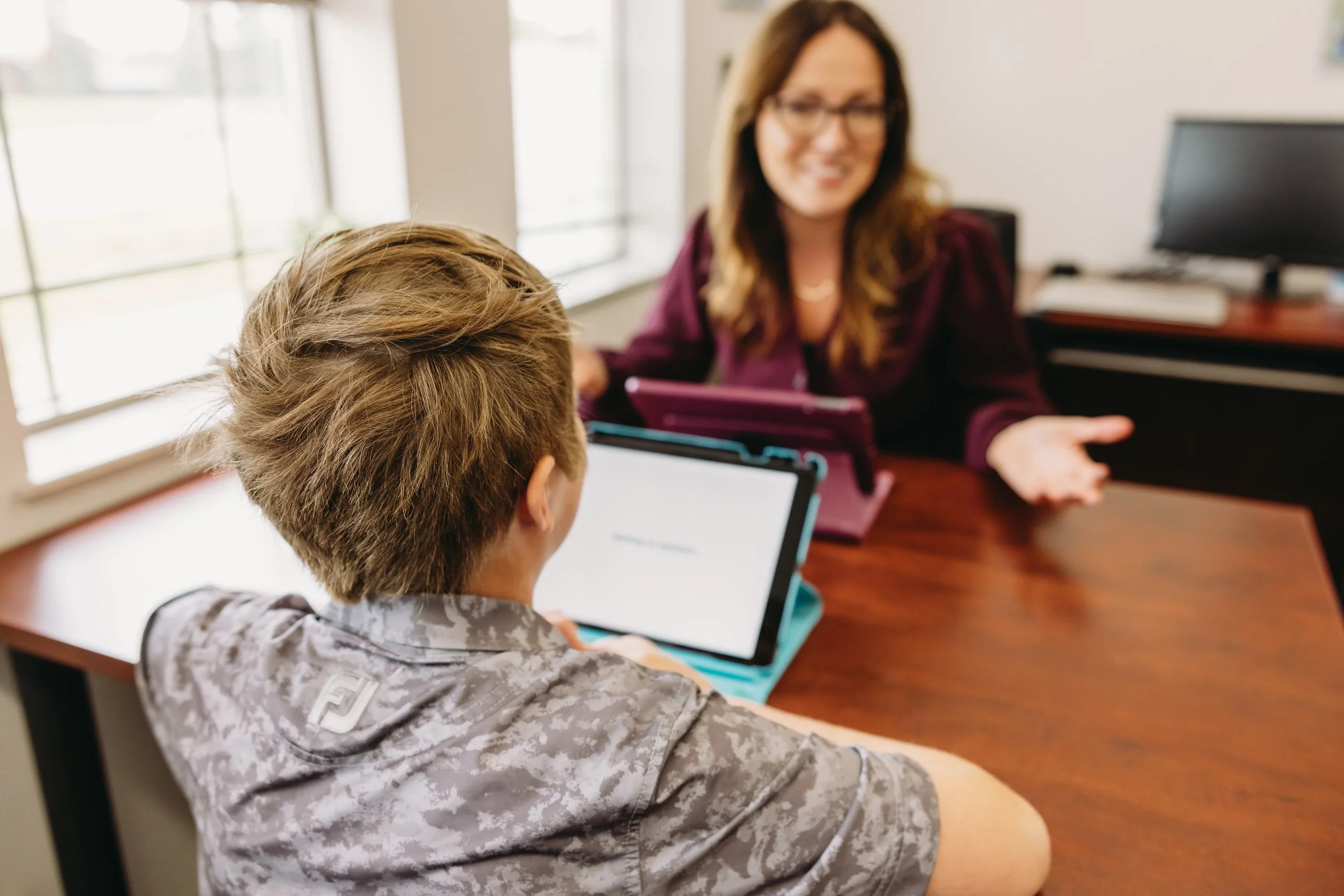 Child completing a tablet-based assessment with a clinician in a neuropsychology private practice, supporting child development psychology and cognitive evaluation.