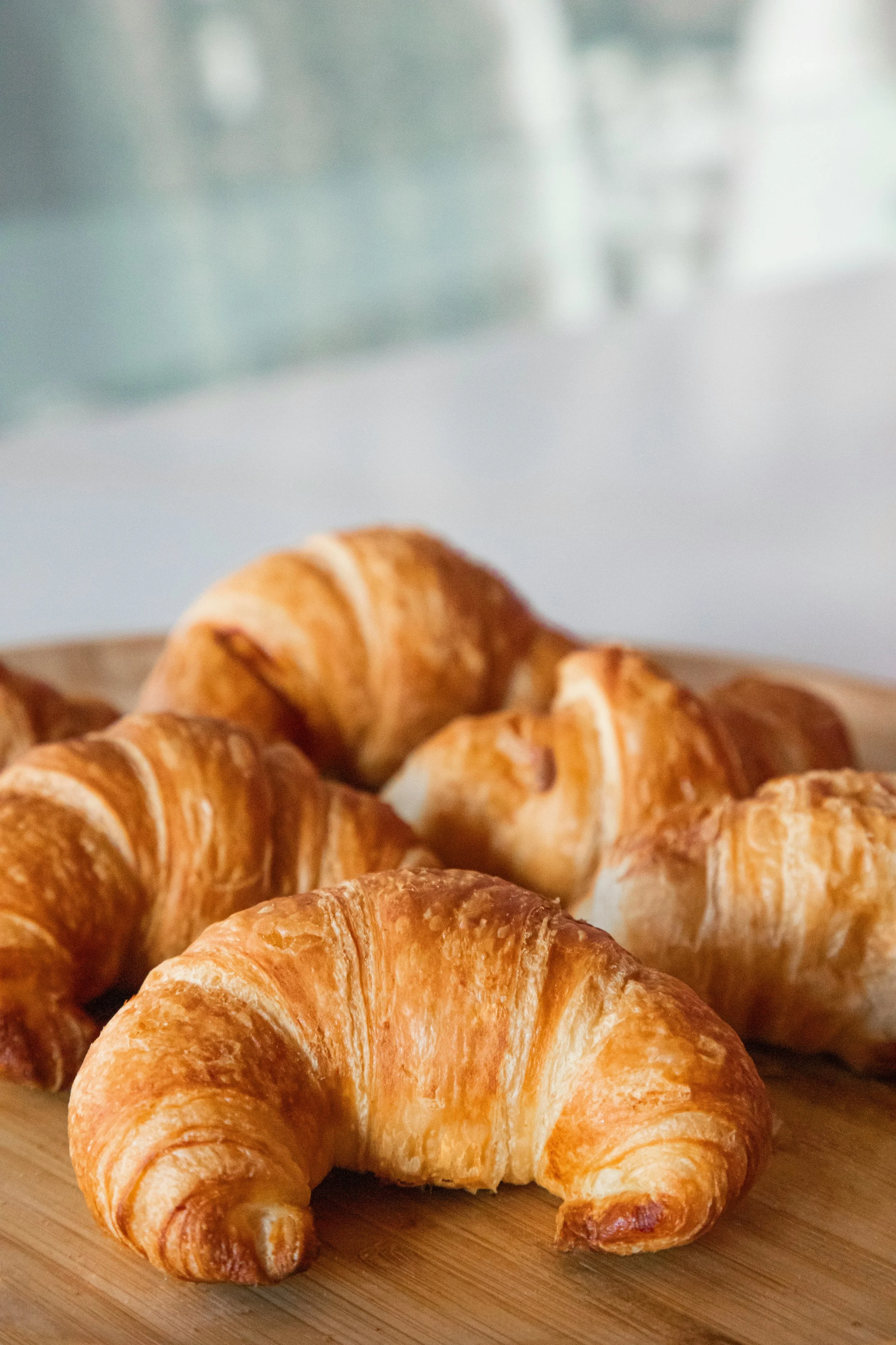 Freshly baked croissants placed on a wooden cutting board.