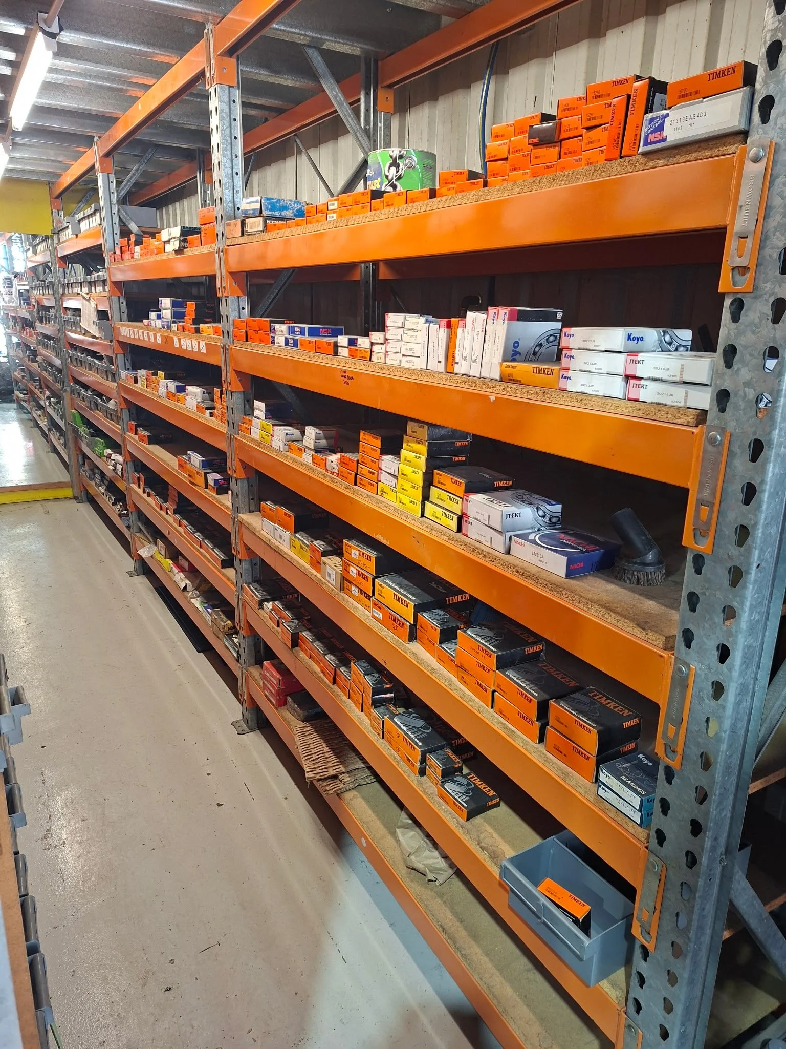 Industrial warehouse shelf with orange and black boxes, various factory parts and supplies.
