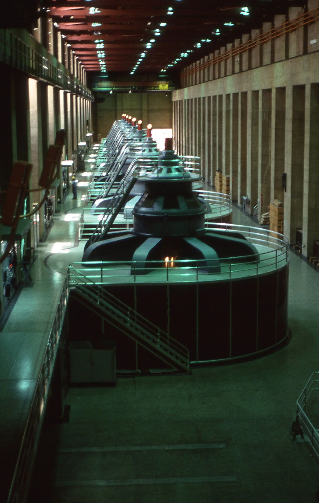 View of a large industrial or power plant interior with multiple large turbines and control panels.
