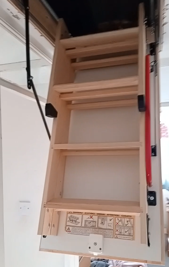 Empty wooden loft ladder with safety labels and instructions at the bottom