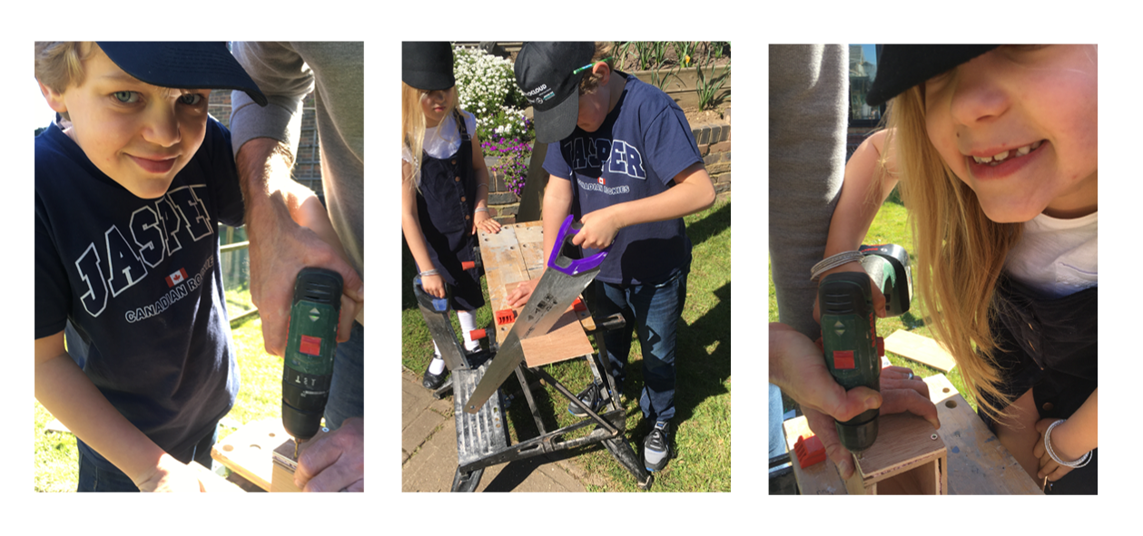 Children and an adult working together on a woodworking project outdoors, using power tools and saws to cut and assemble wood.