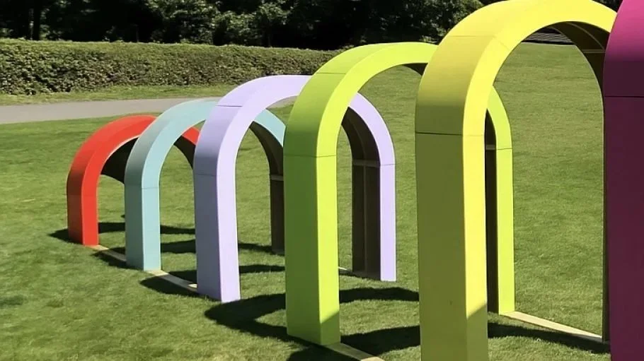 Colorful rainbow-shaped arches arranged in a row on a grassy field.