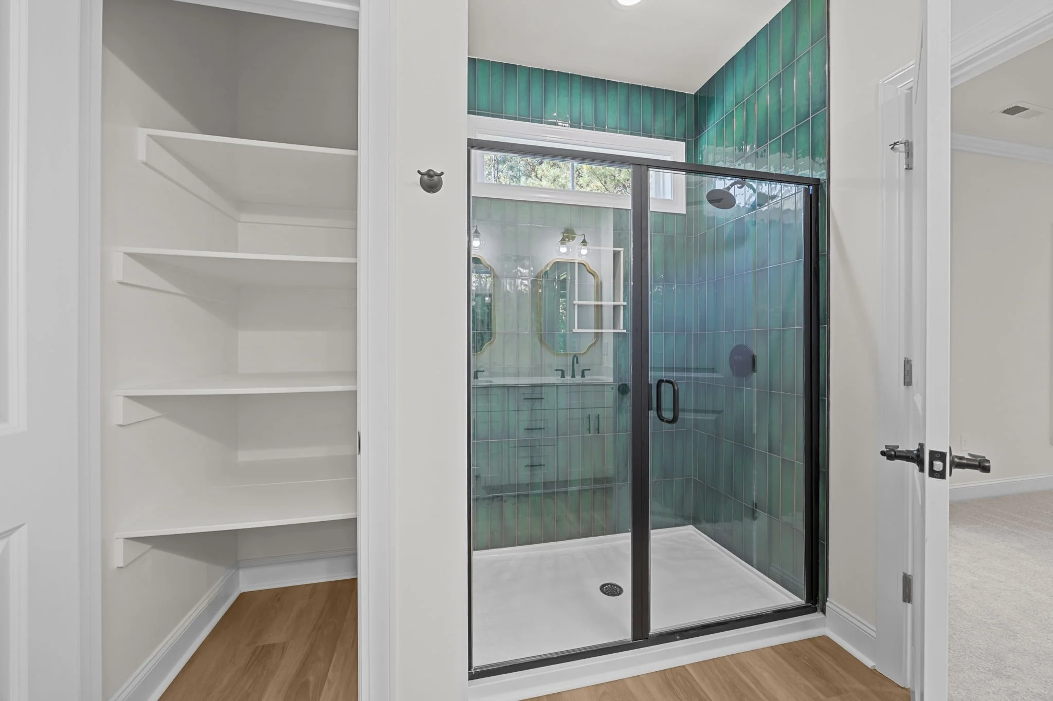 A modern bathroom with a glass shower enclosure featuring green tiles on the walls.