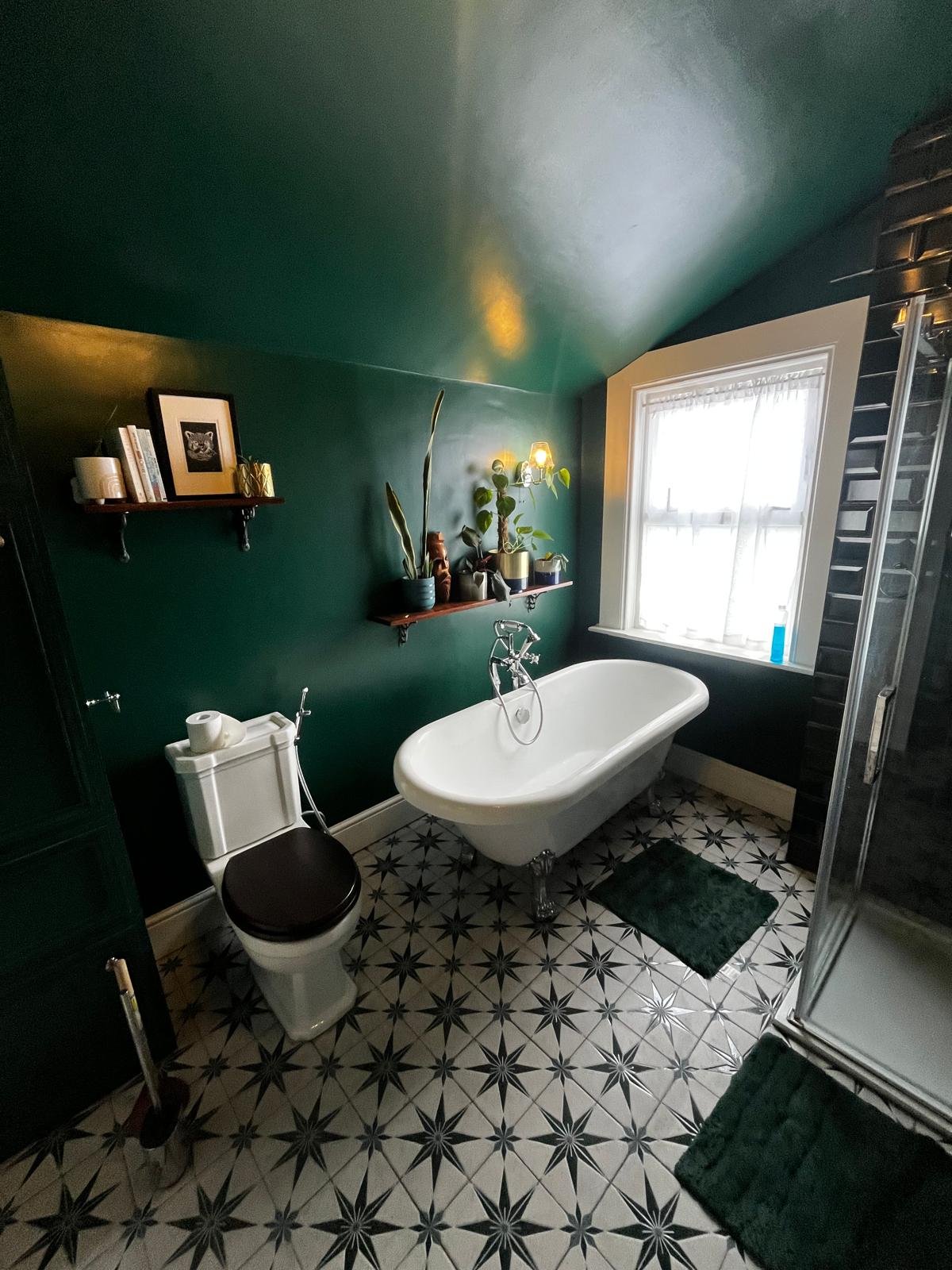 Roll-top bath installation against dark green walls with green metro tiles and star tile flooring in a classic Bristol terrace property in Easton.