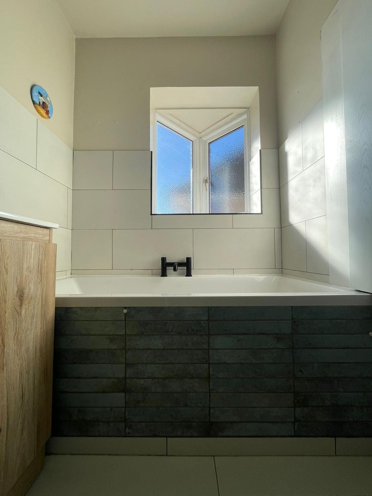 Bespoke tiled bath panel with natural stone wall and floor tiles in bathroom