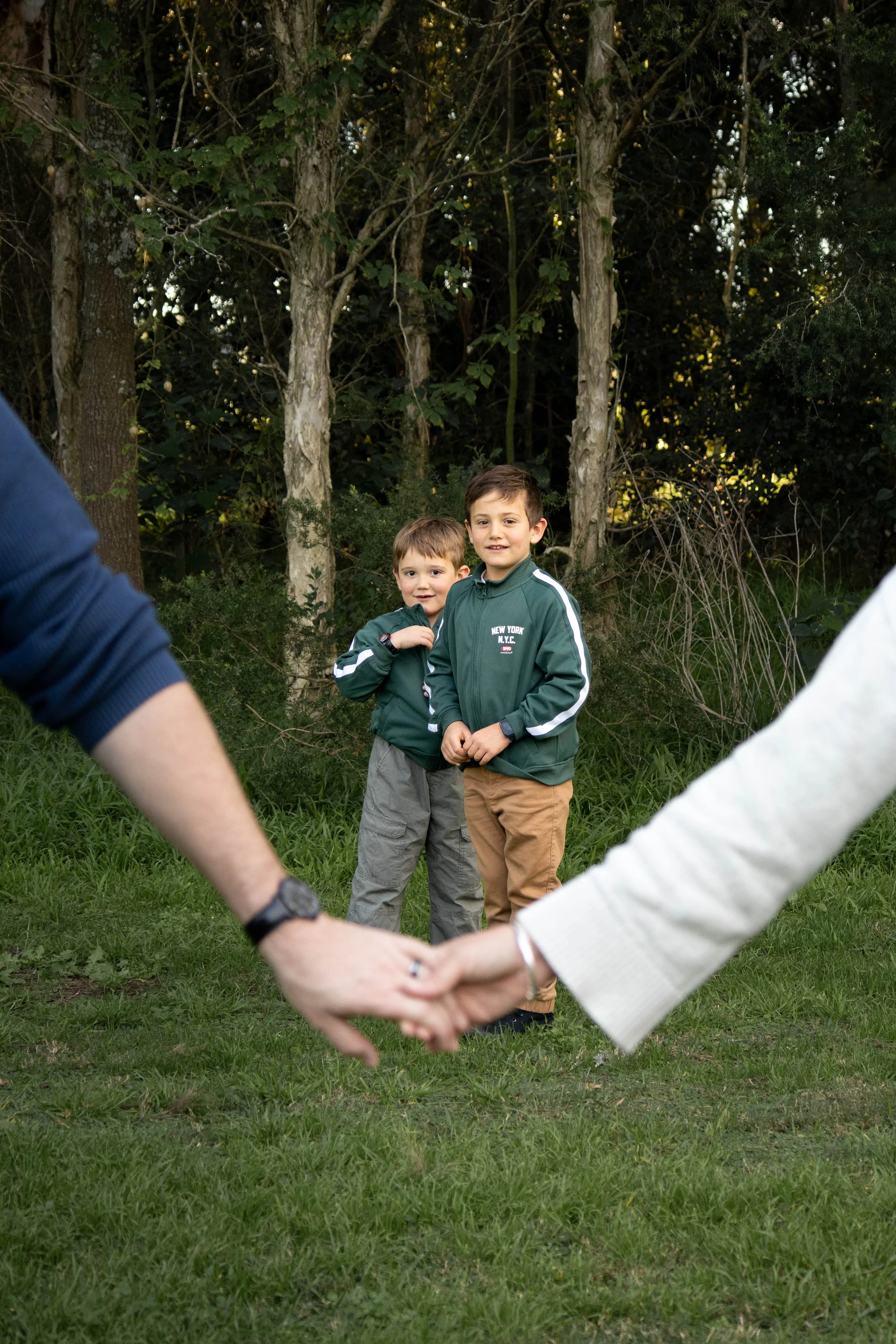 Two boys standing outdoors, one wearing a green jacket with