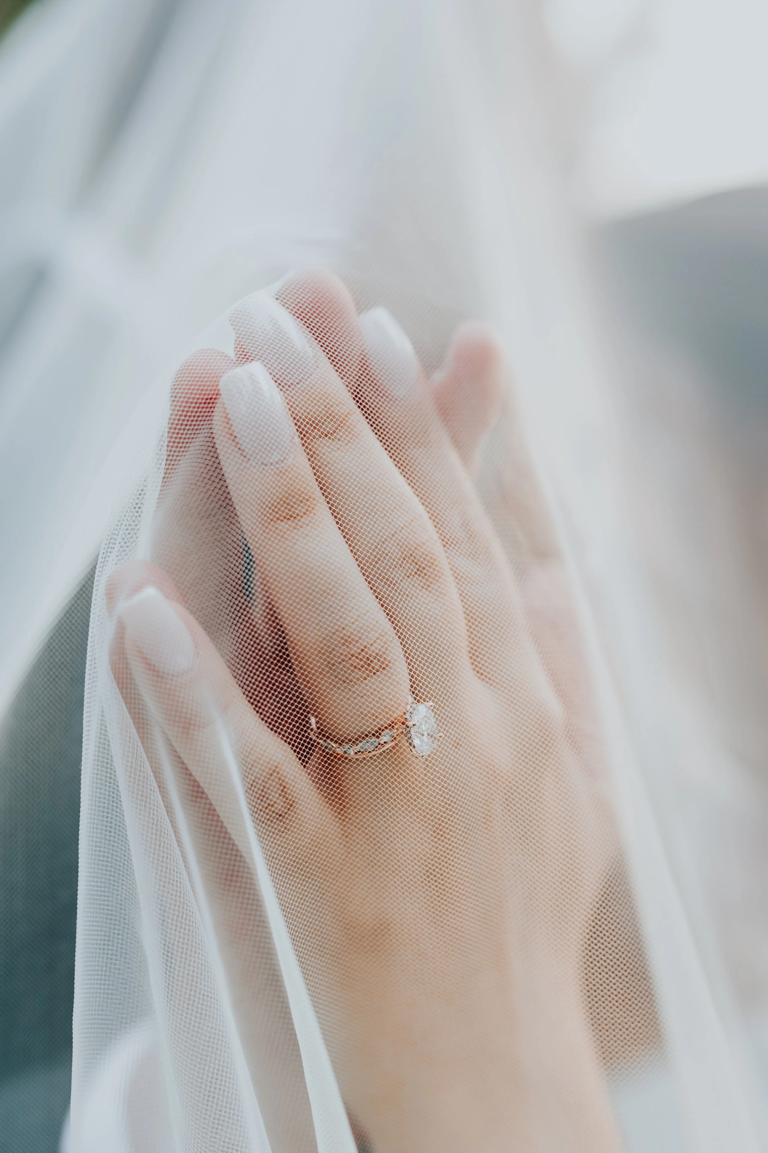 A person wearing white gloves touching a sheer white fabric with sunlight shining through.