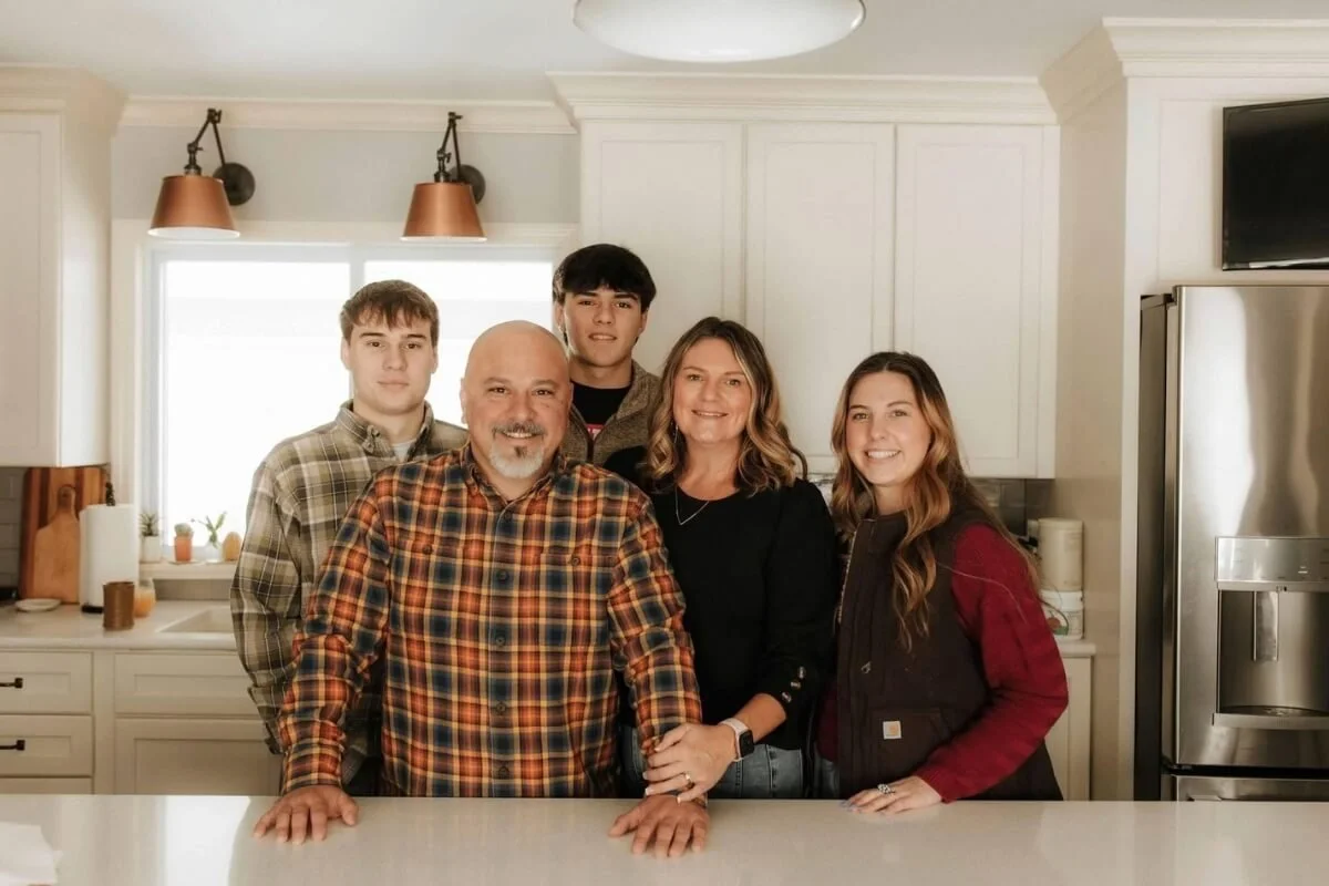 The Colvin Family in a kitchen, two parents with three children and a refrigerator in the background.