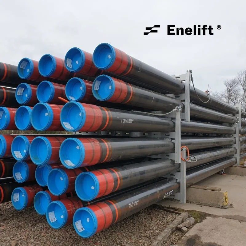 Stack of large steel pipes with blue and red protective caps on a construction site, branded with Enelift.