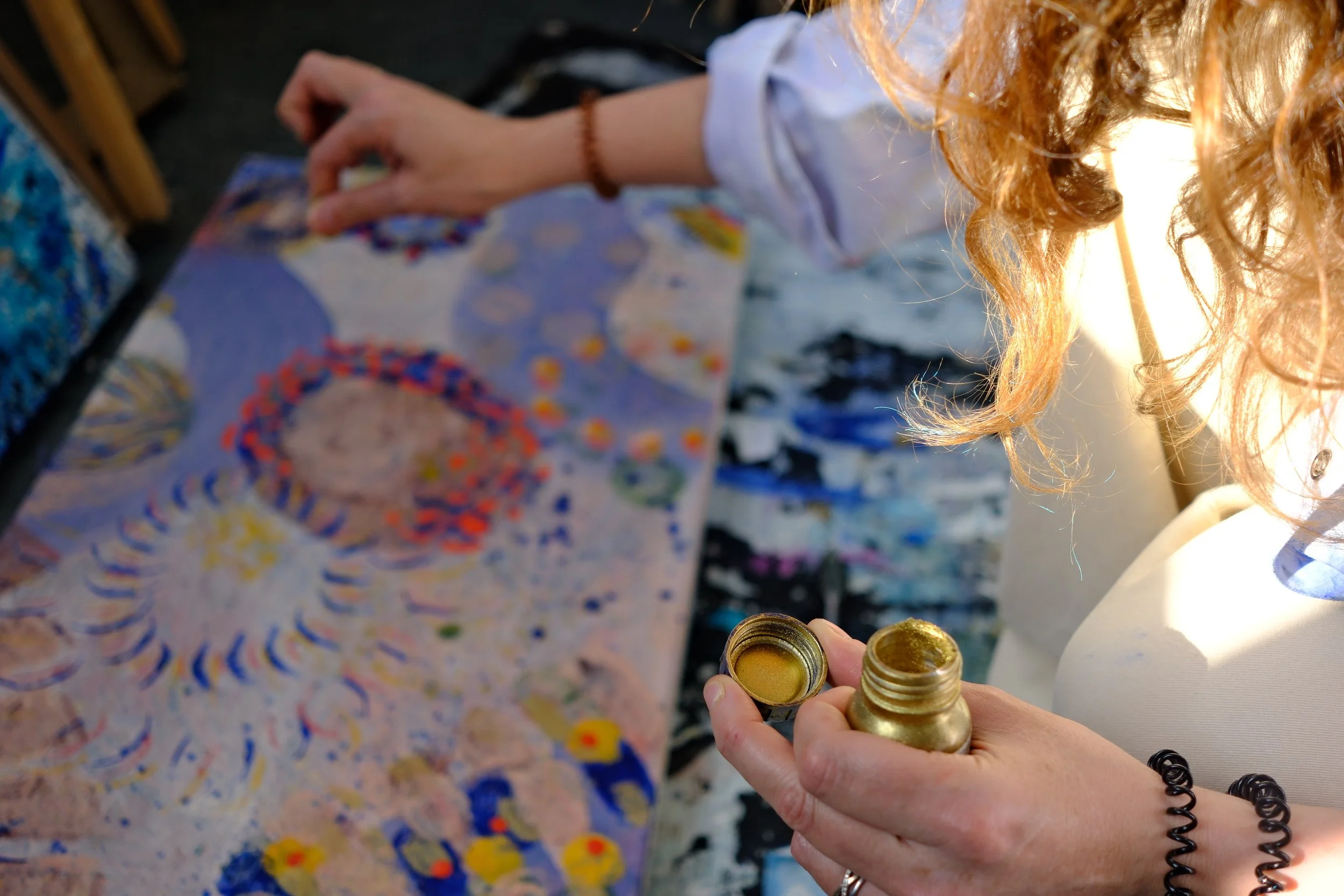 Artiste tenant un pot de pigment doré au-dessus d'une toile colorée