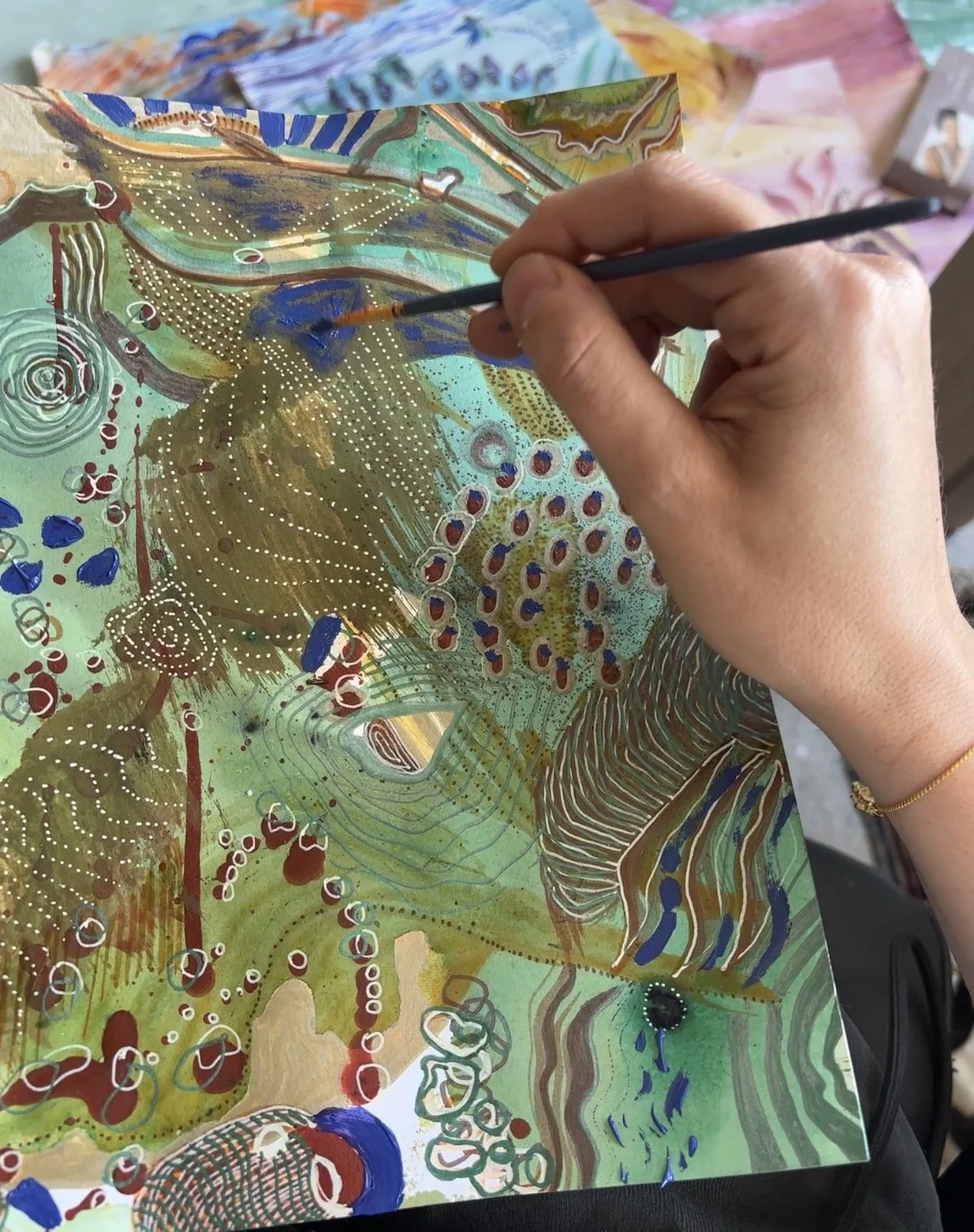 Main peignant des motifs colorés sur une œuvre abstraite