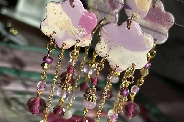 Pair of decorative earrings with purple and pink beads and floral-shaped tops.
