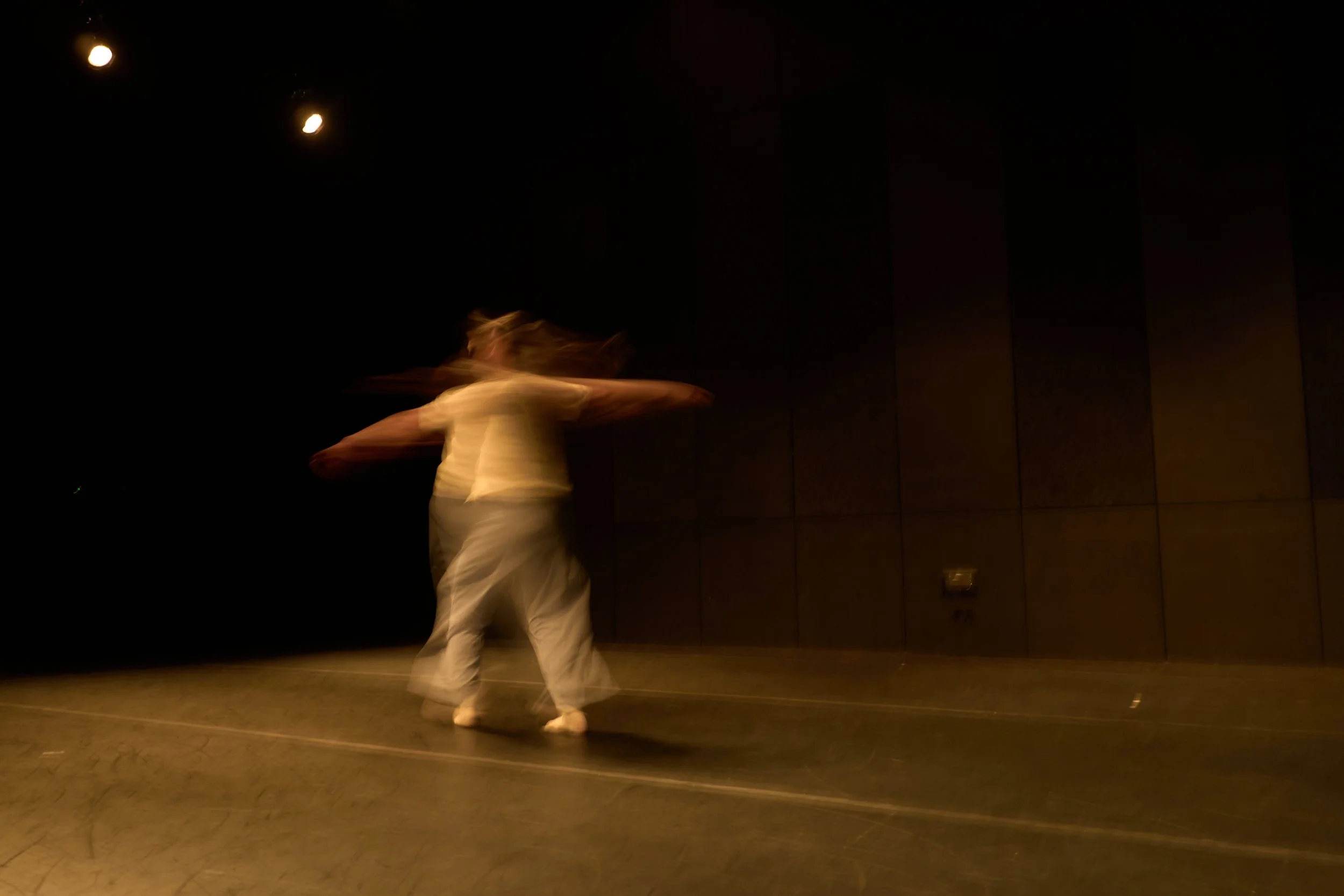A person spinning in a dance studio at night, with motion blur and a dark background.