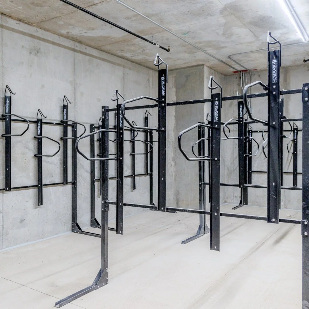 Empty indoor parking garage with black bike racks attached to the concrete wall and floor.