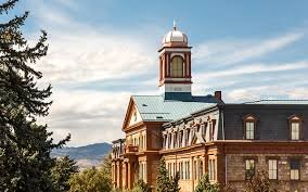 Historic brick building with a dome and clock tower, set against a partly cloudy sky.