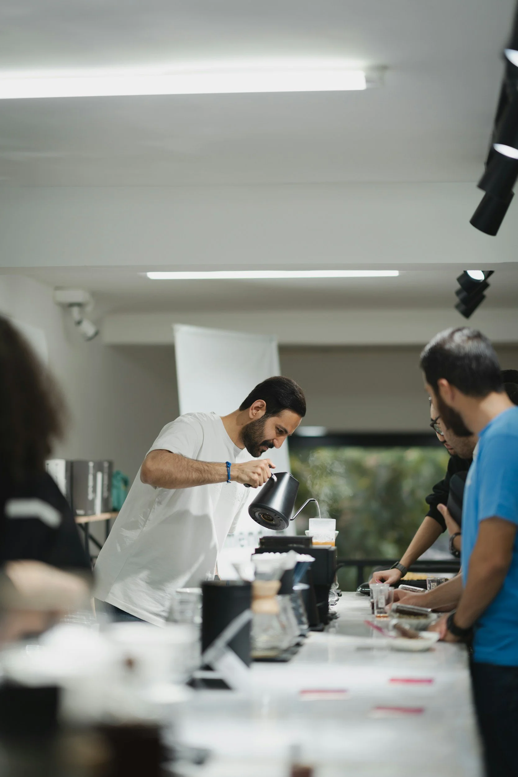 A man brews coffee with church brewing volunteers at a coffee tasting.