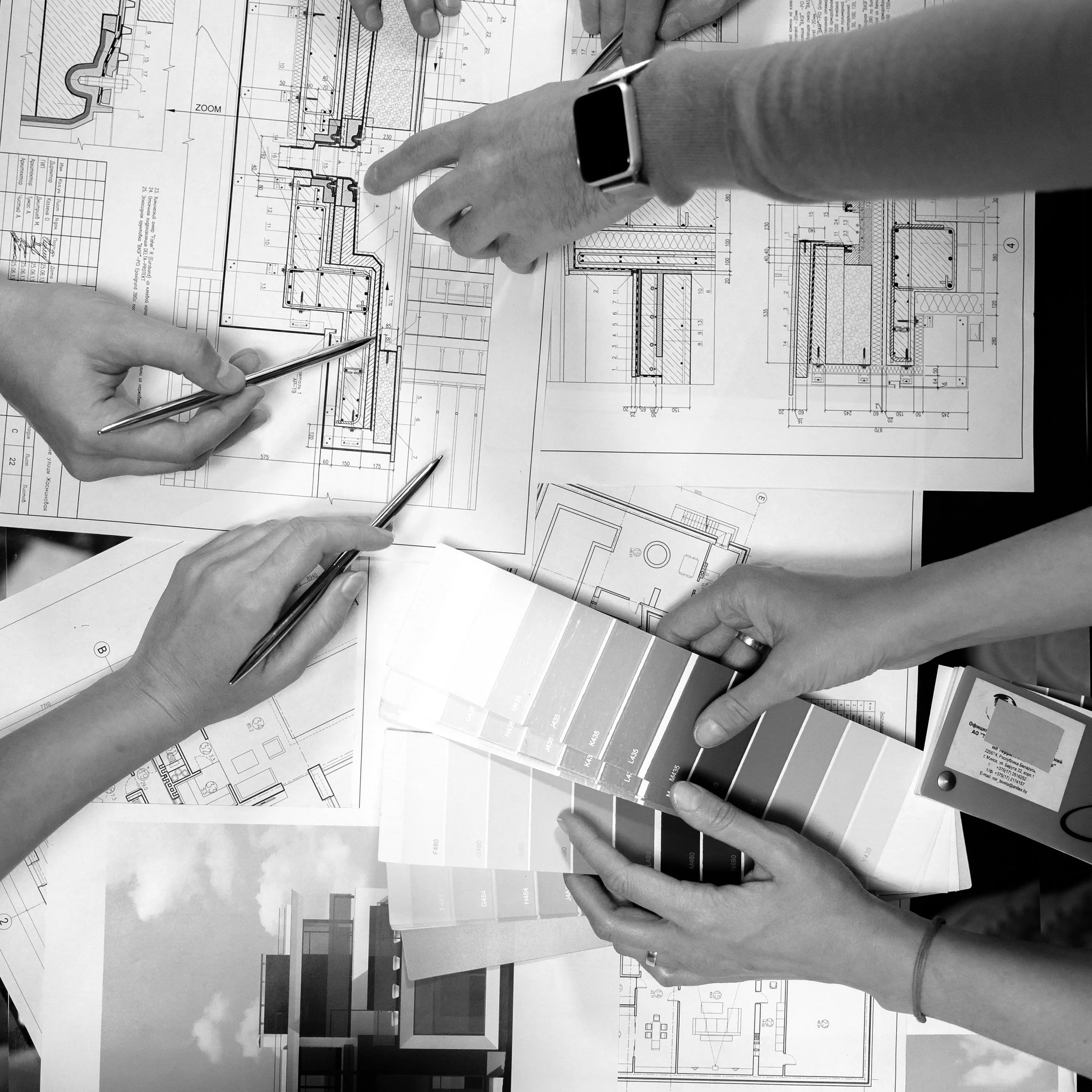 Personnes examinant des plans d'architecture sur une table, choisissant matériaux et couleurs compatibles avec le patrimoine ancien.