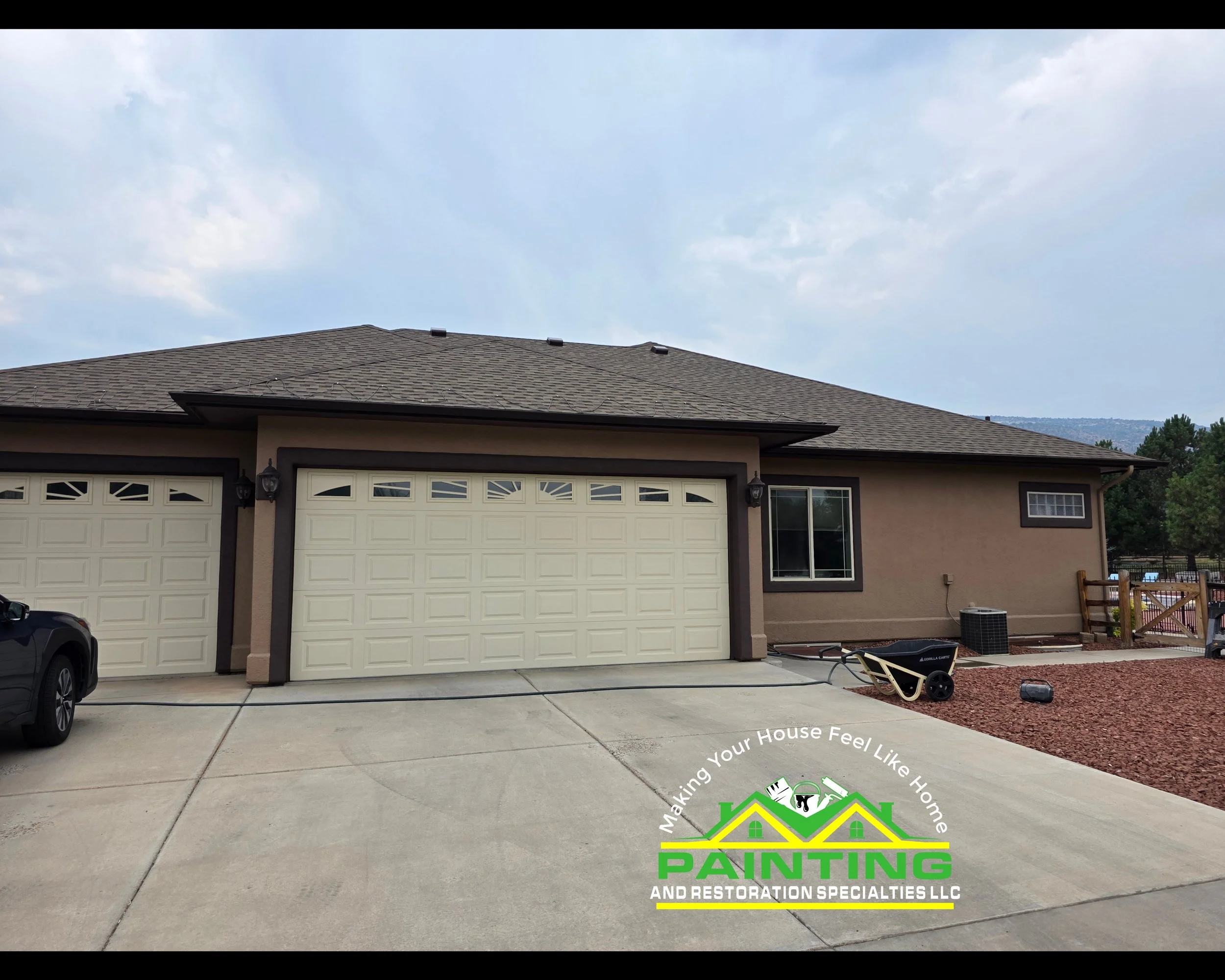 Photo of a house with a garage and driveway, showing the roof and part of the backyard with some outdoor equipment. The company logo for painting and restoration specialists LLC is at the bottom.