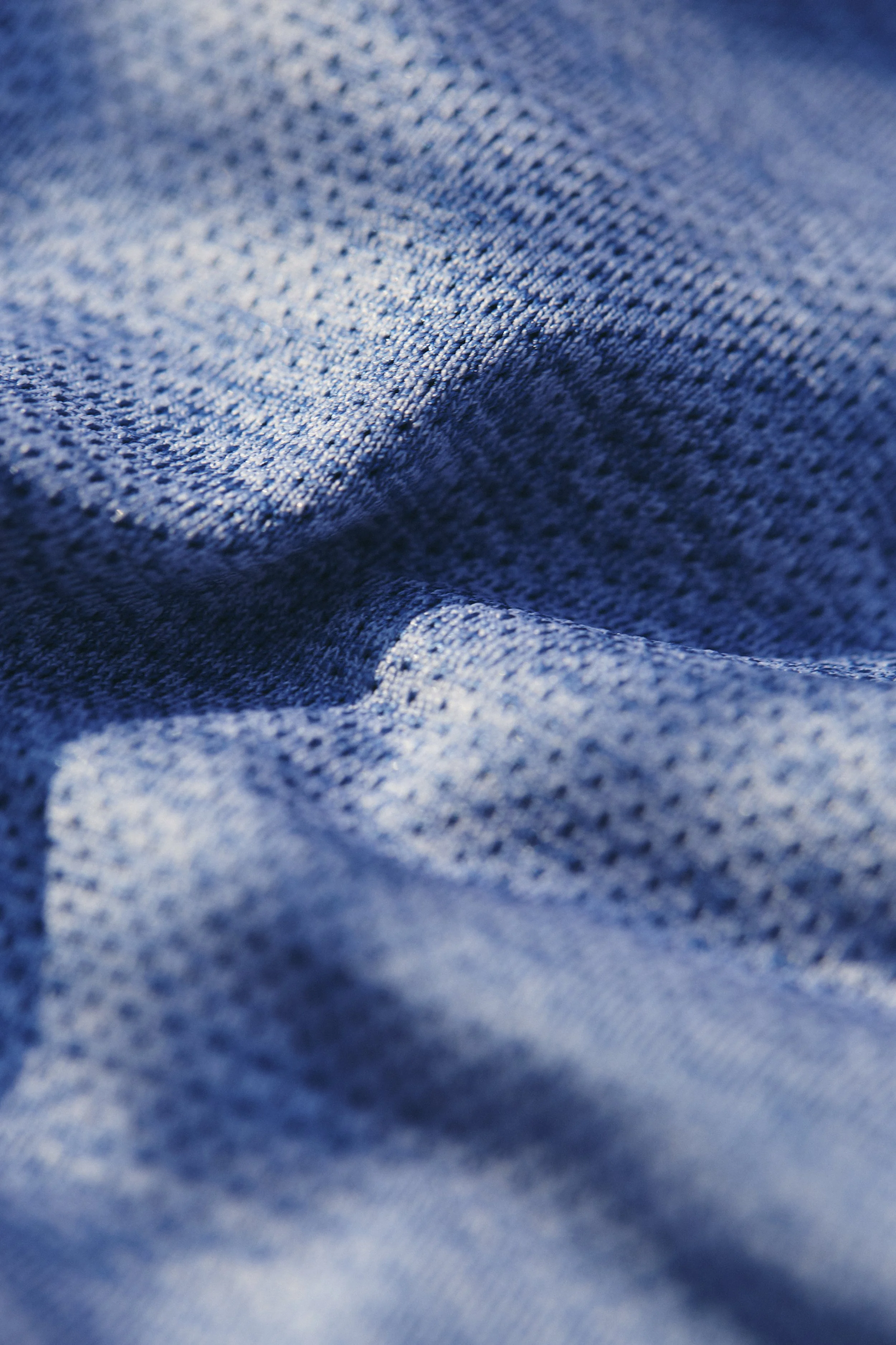 Close-up of MB Sport blue sportswear fabric with visible weave and texture.