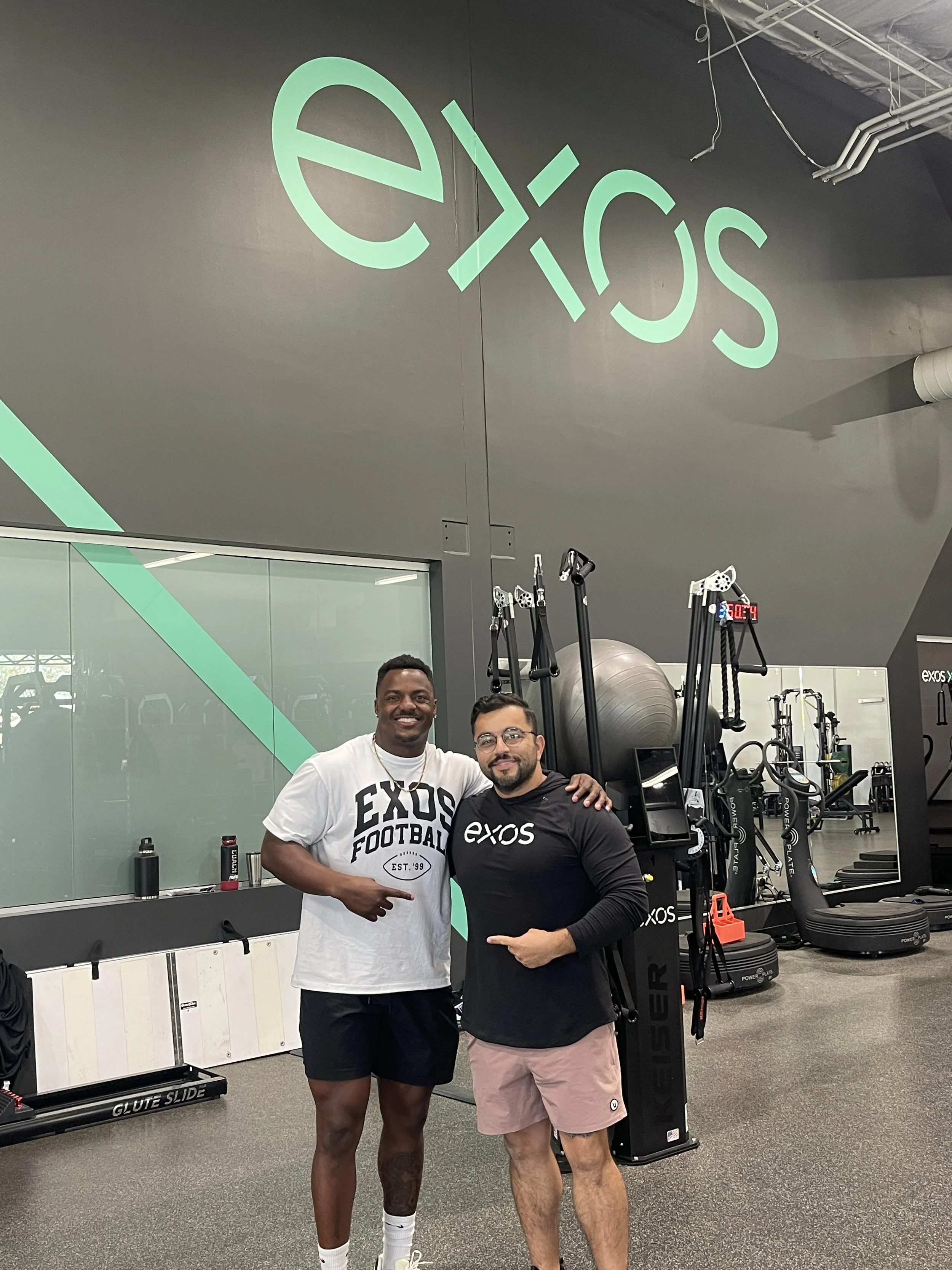 Andre Whitely posing in front of the EXOS gym with co-worker Naveed Shan.