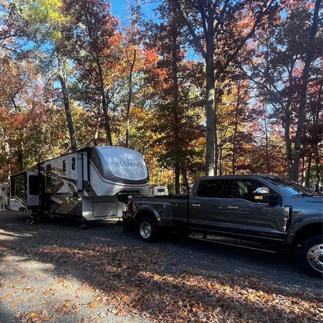 Truck towing a 5th wheel RV on a paved road in the fall at Waynesboro North 340 Campground