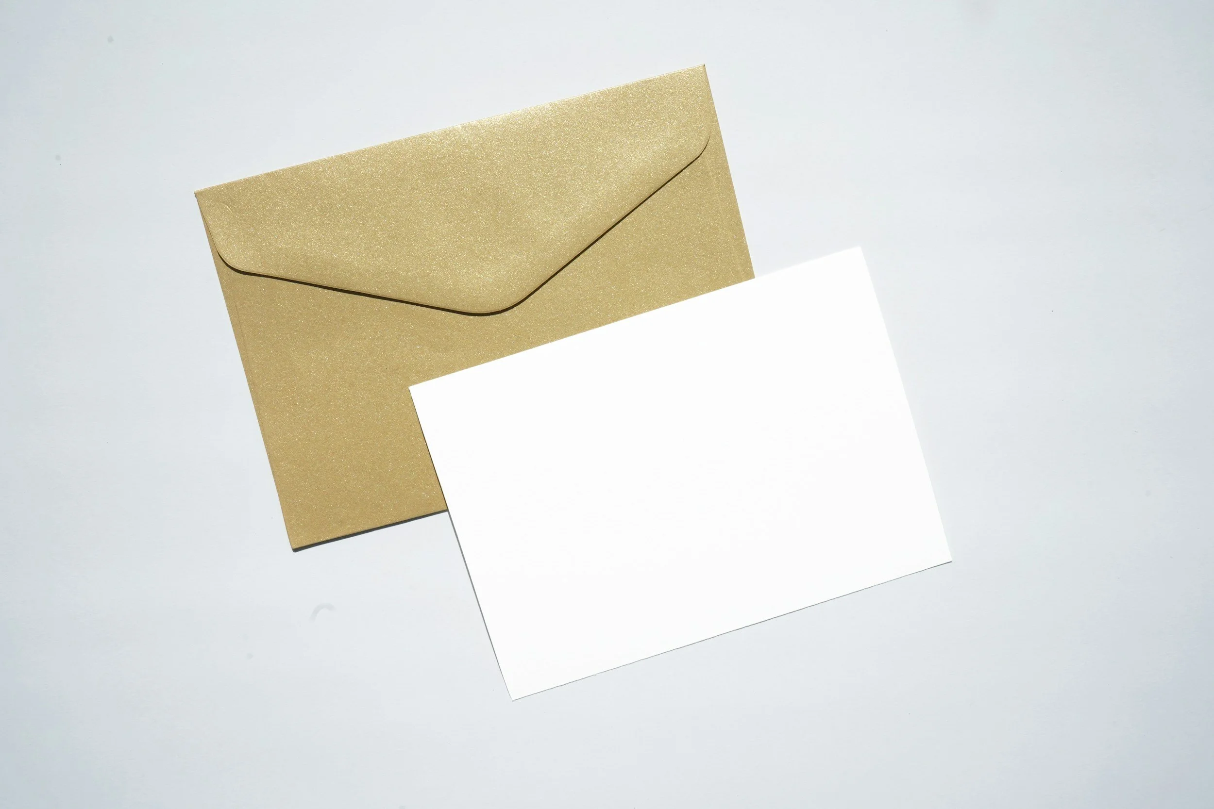 An envelope with a shimmering gold appearance and a blank white card partially inserted.