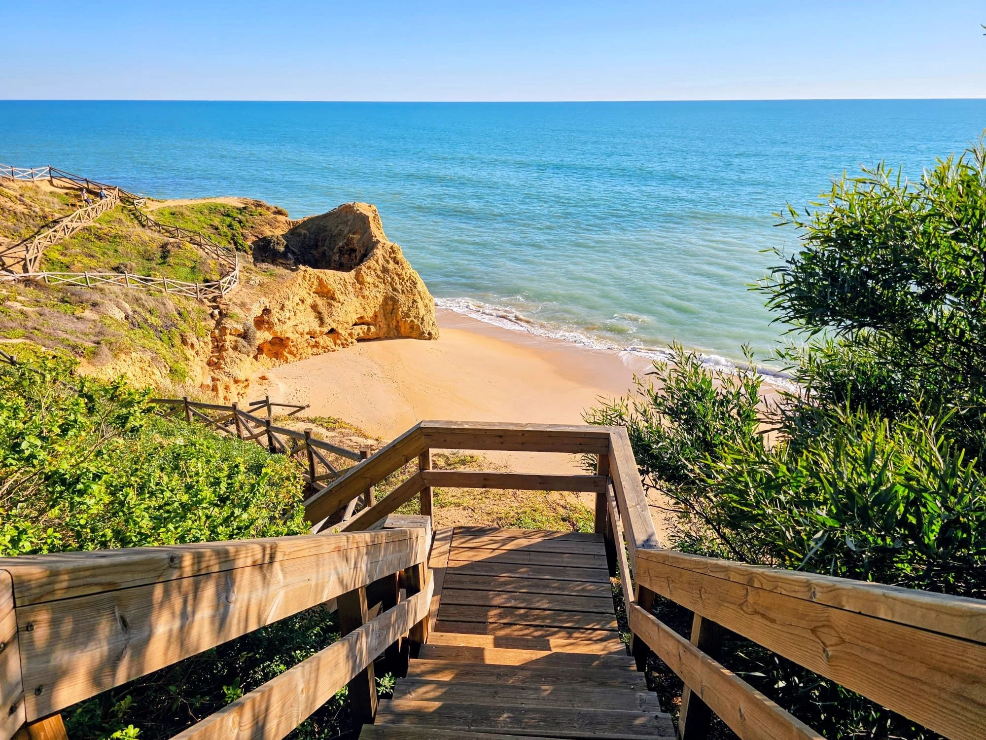 Wodden Stairs descending to an empty beach surrounded by cliffs in the Algarve