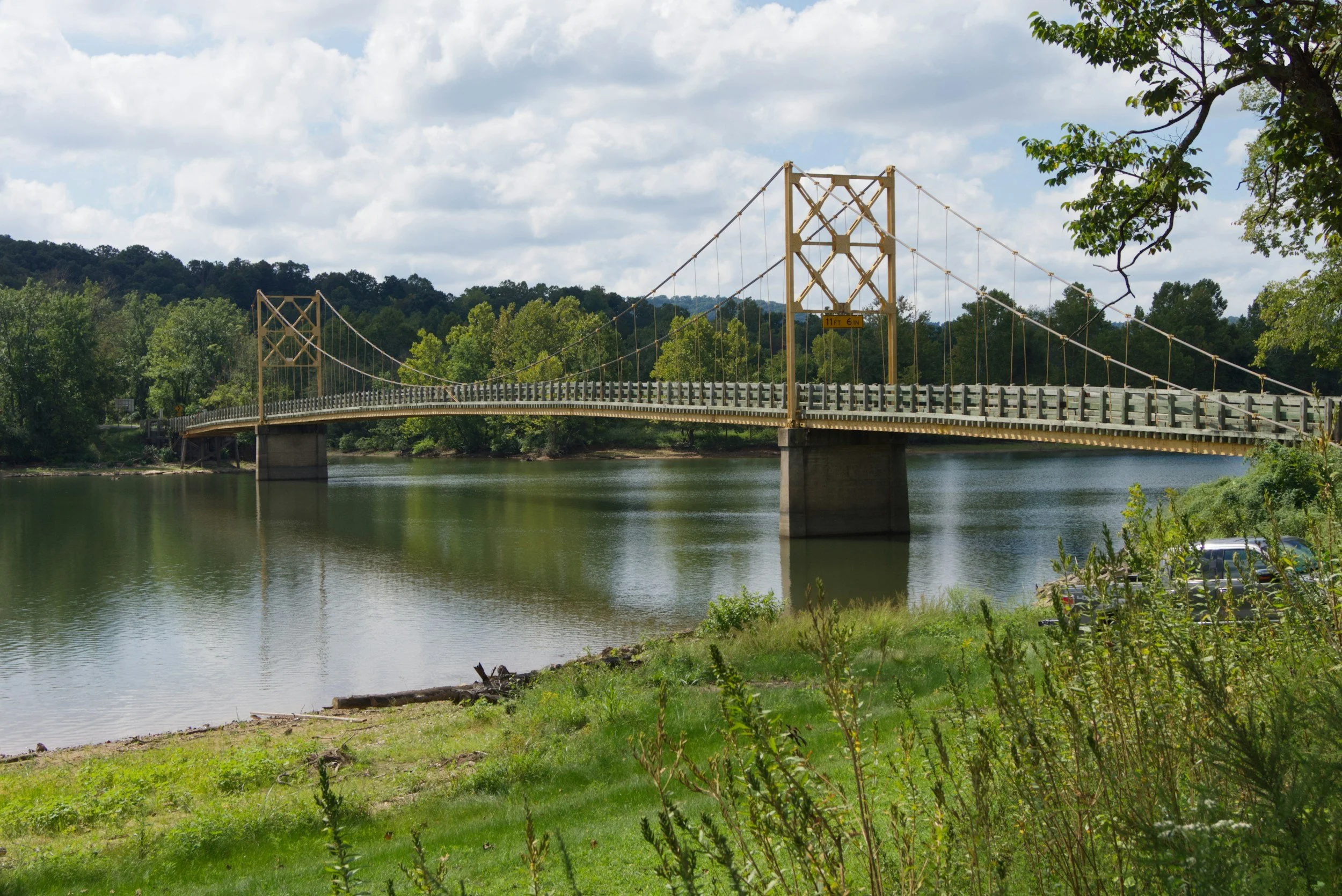A yellow suspension bridge over a calm river in Arkansas.