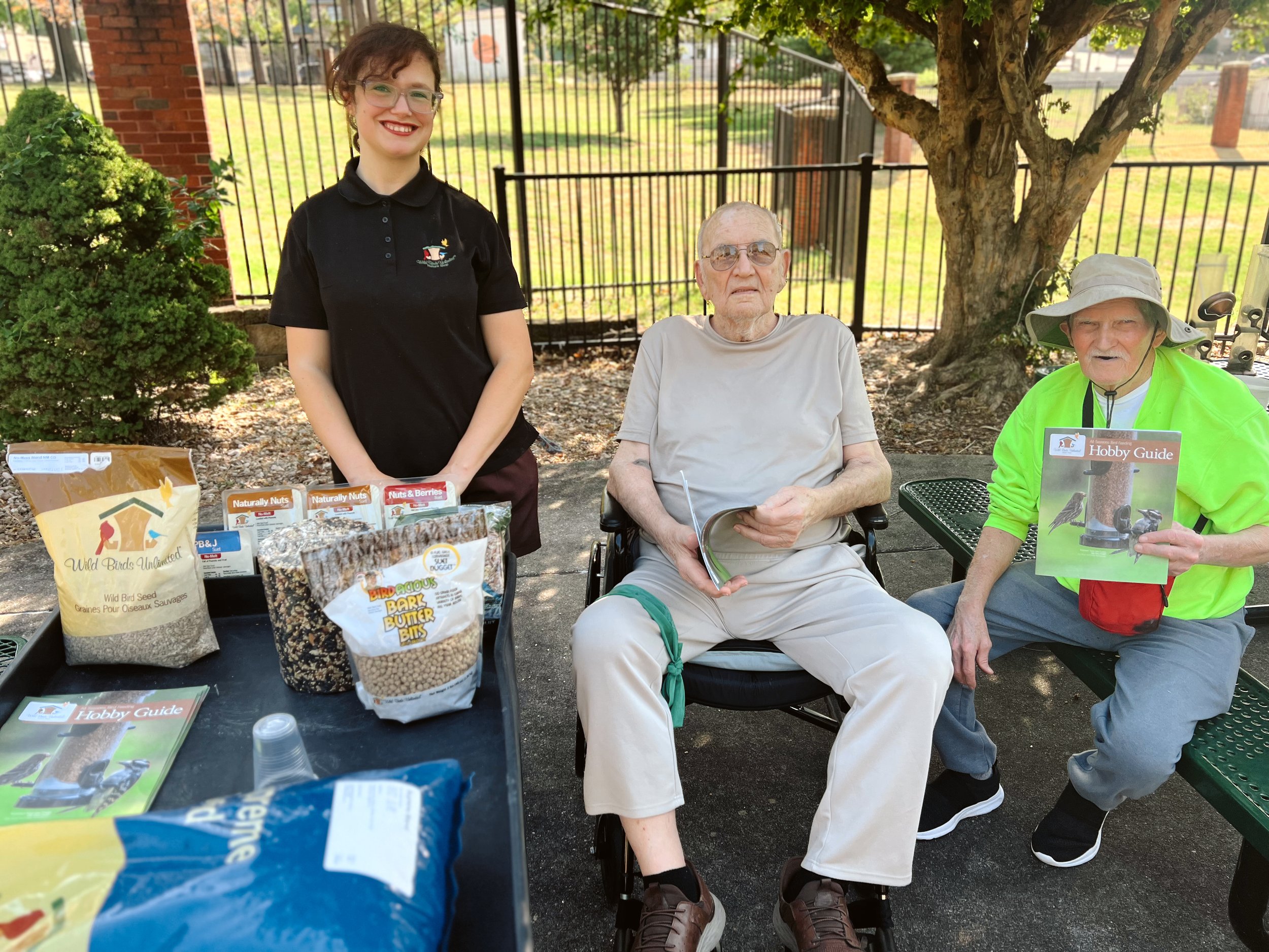 Residents pose for a photo with a volunteer that is teaching them about local birds. 