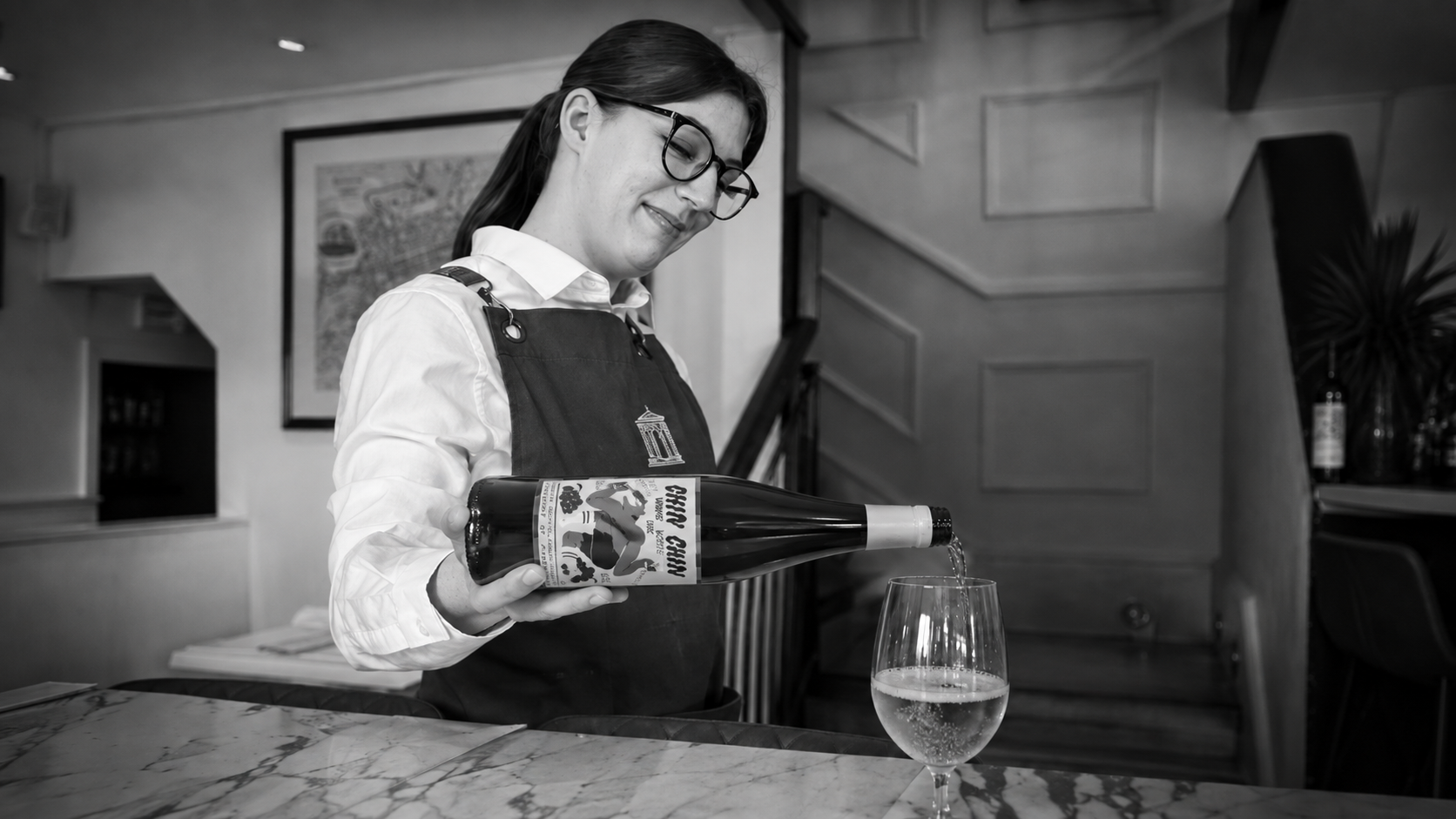 Society server pouring sparkling wine at the restaurant’s marble bar.