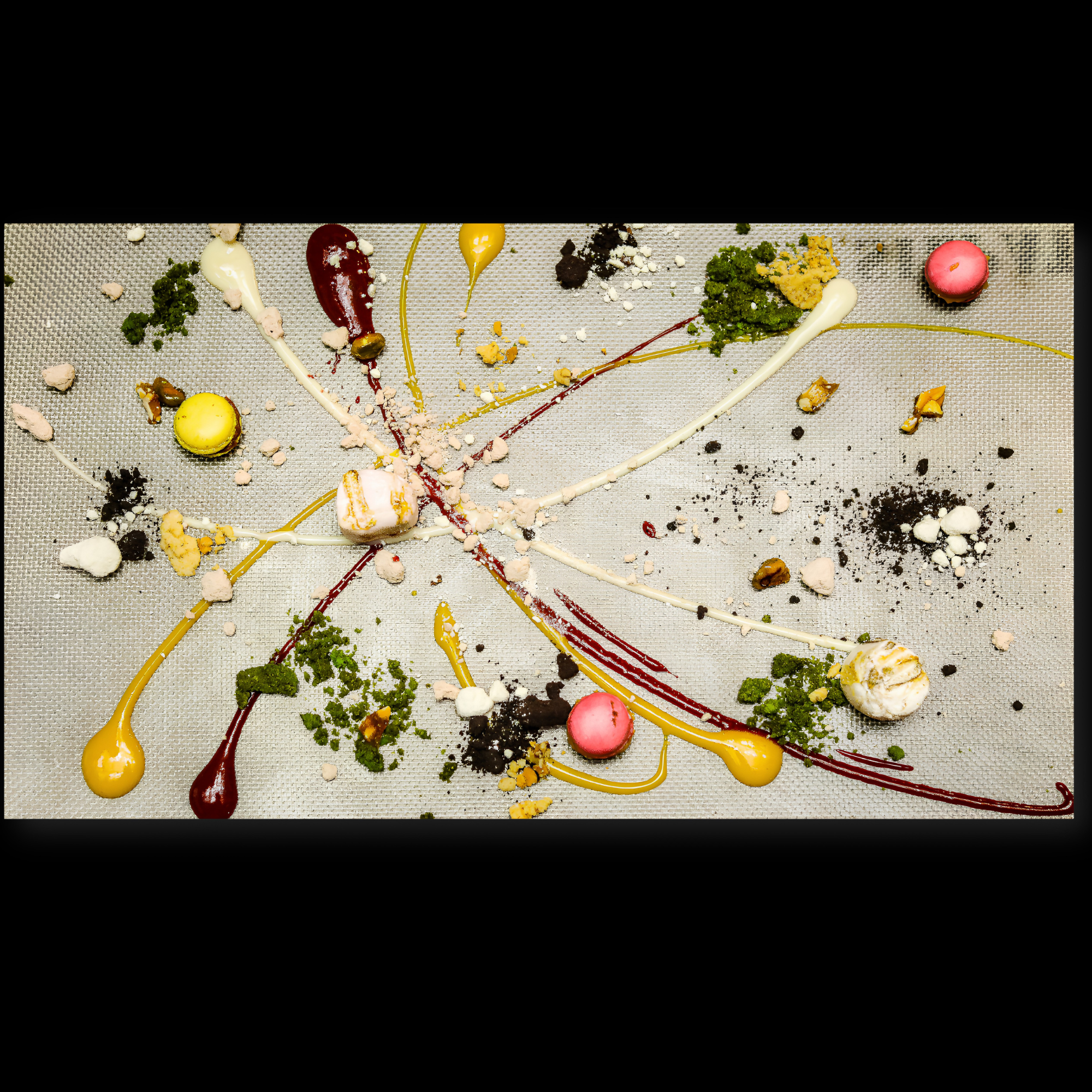 Abstract art piece featuring colorful drizzles and splatters of paint on a textured surface.