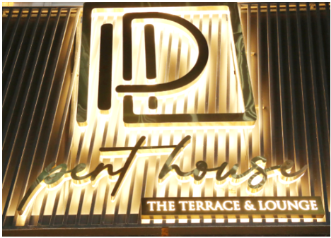 Neon sign reading 'IDent House' and 'The Terrace & Lounge' on a wall with vertical wooden slats.