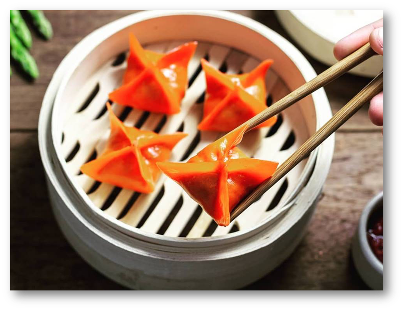 Yellow bamboo steamer basket containing orange star-shaped vegetable dumplings.
