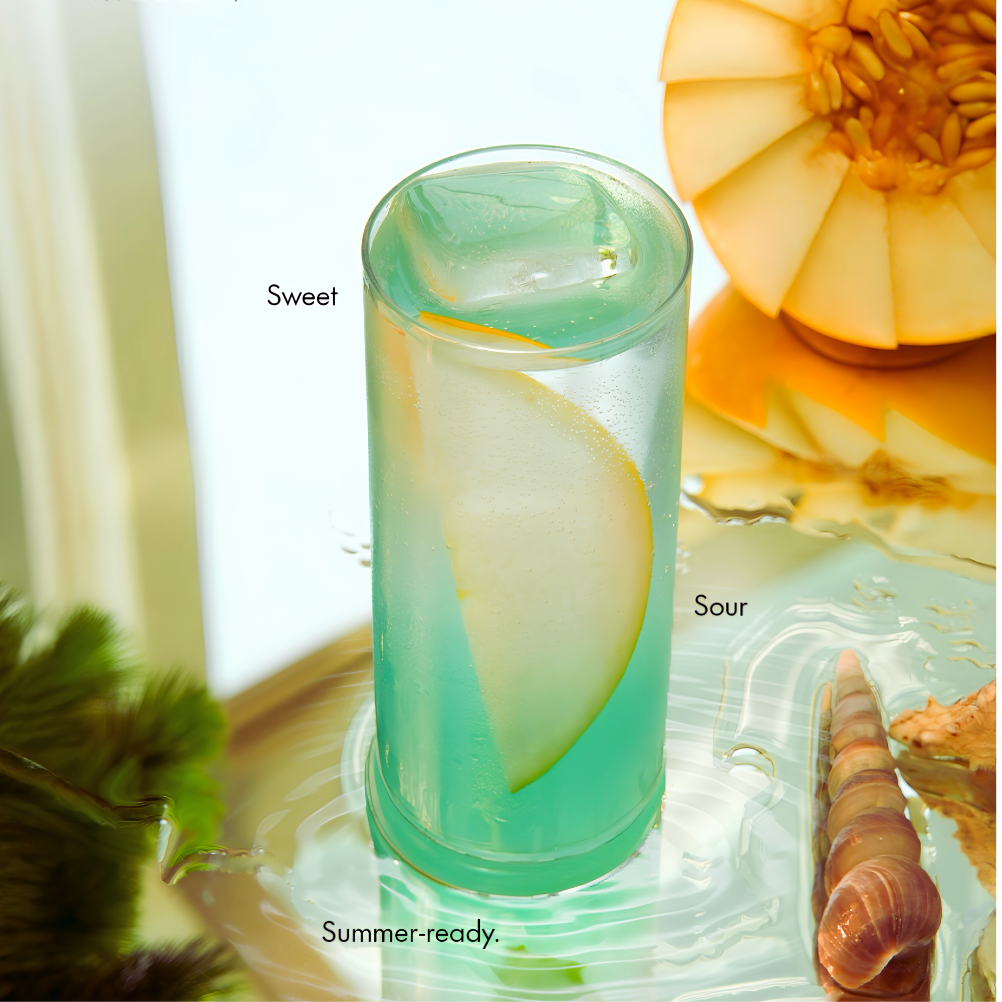 A glass of icy green beverage with a lemon slice and pineapple in the background, with partially visible text 'Sweet' and 'Summer-ready'.